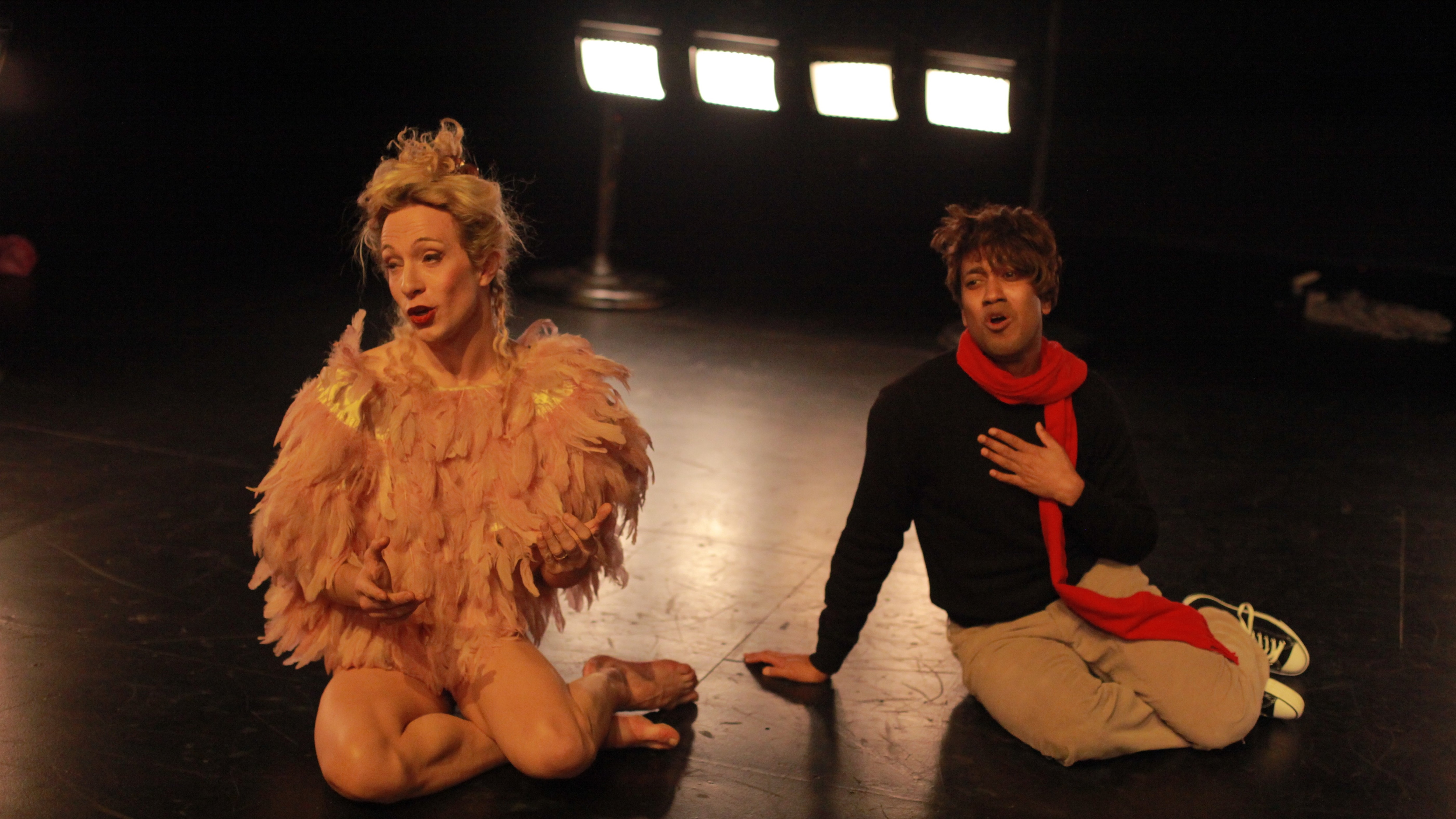 Two dancers sitting on the floor, mouths agape