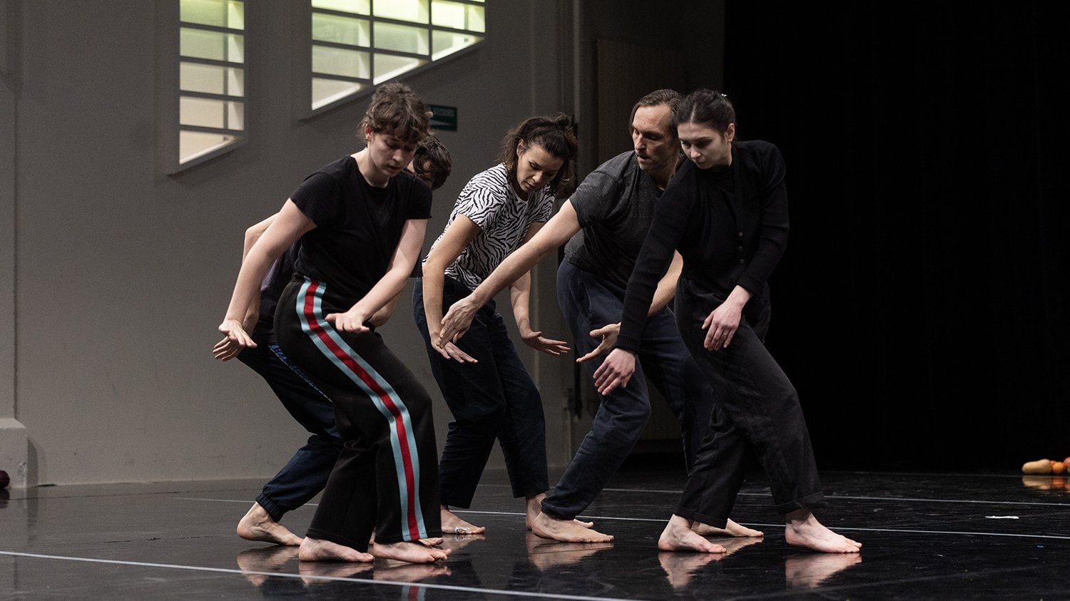 five dancers in a row in the same position, looking at their hands