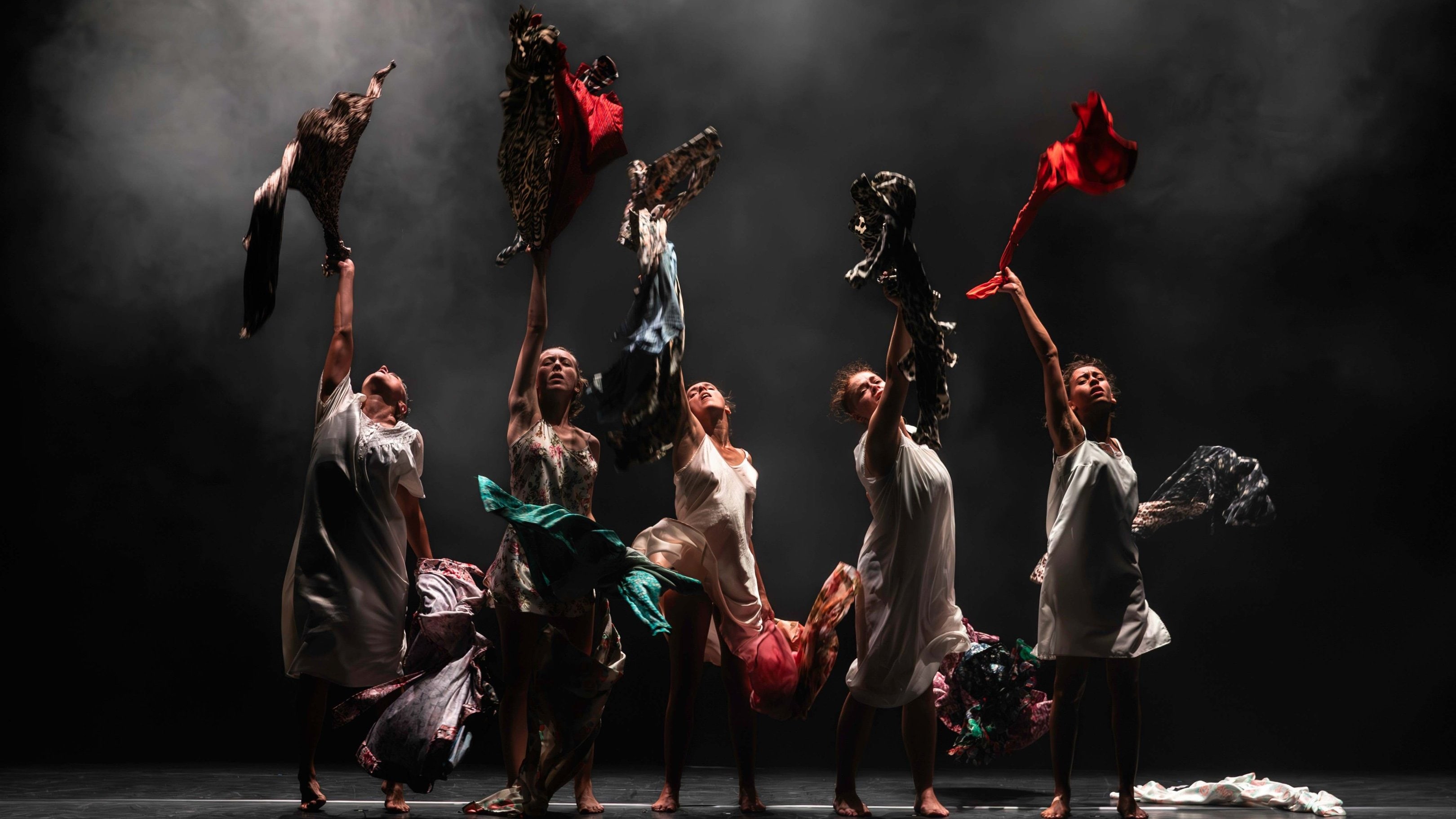 Four women lined up throwing shirts and dresses upwards