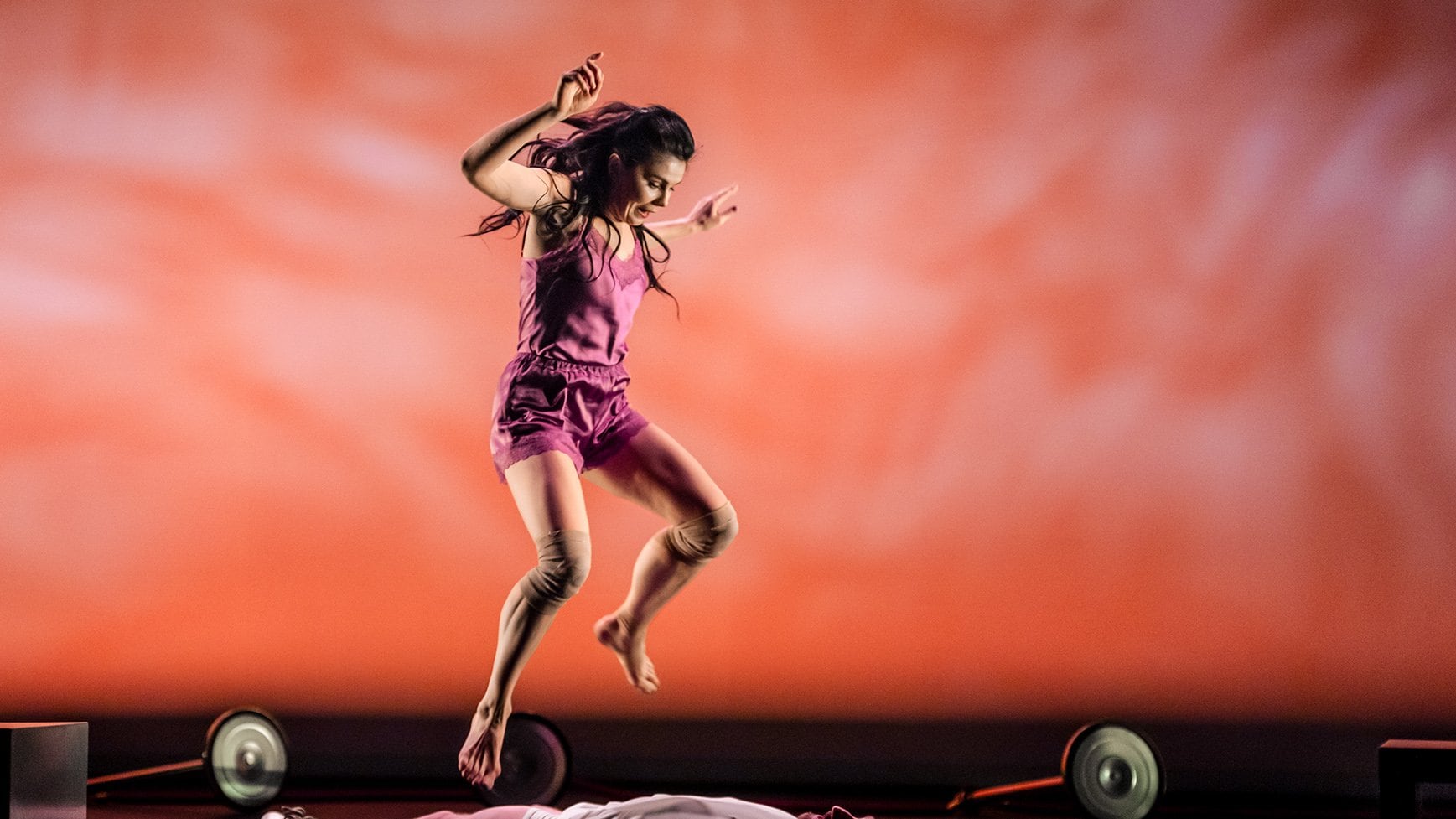 Une danseuse en train de sauter, en dessous d'elle, un homme allongé sur le dos