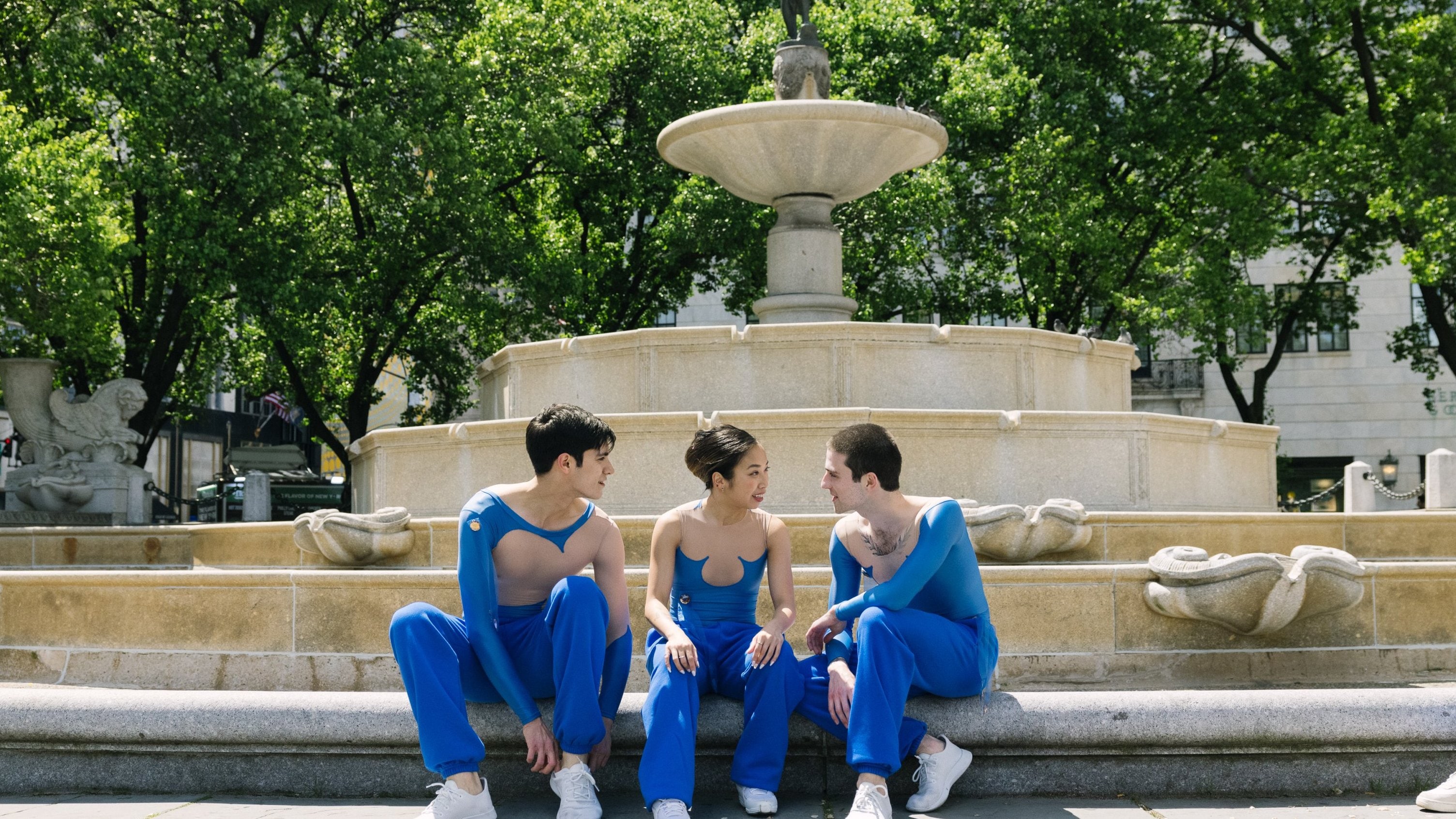 3 danseurs assis devant la Pulitzer Fountain