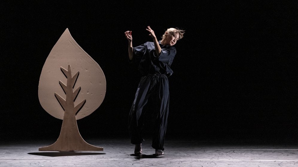 danseuse sur scène à droite d'un arbre en carton