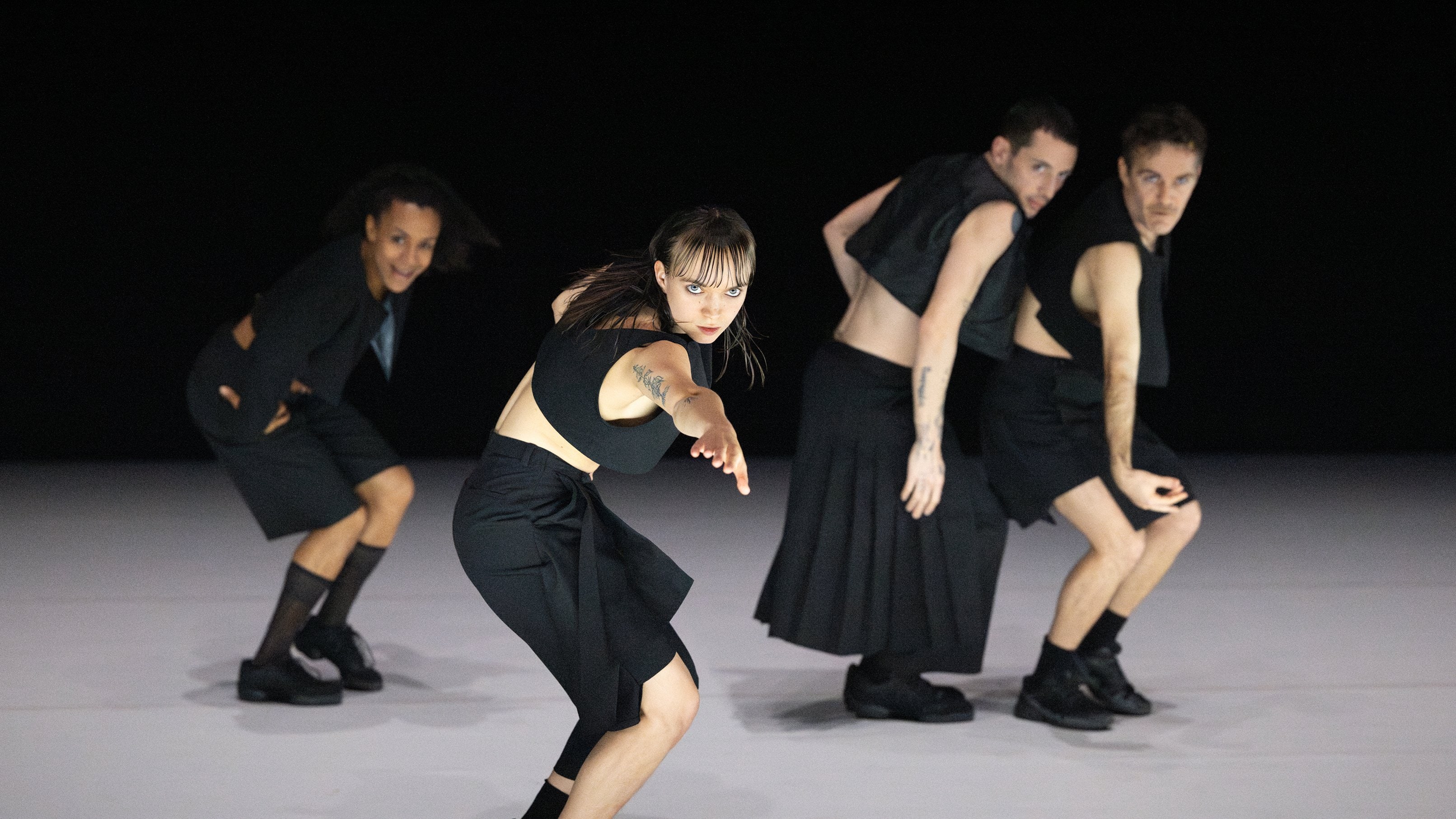 4 dancers performing on stage wearing black