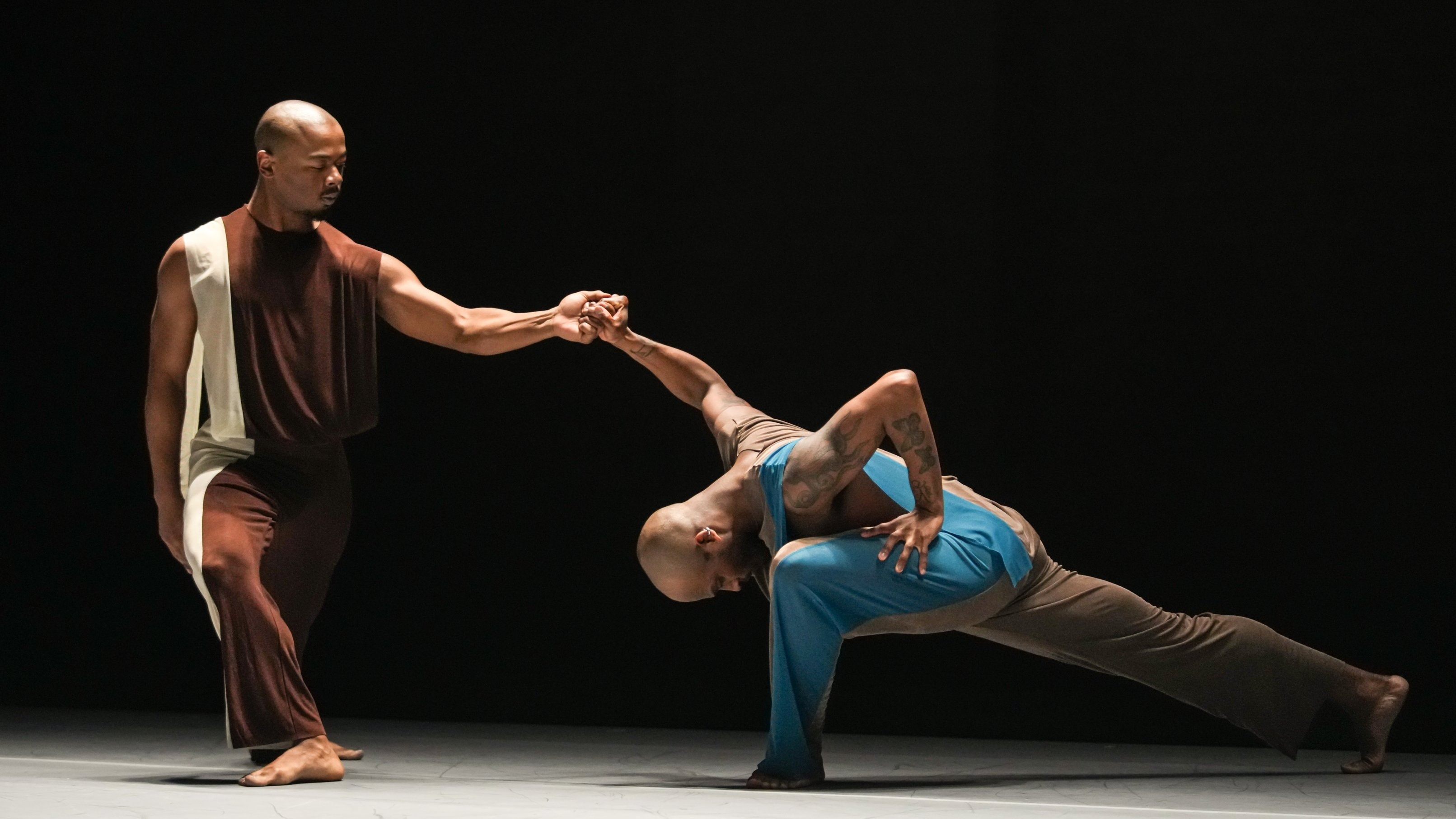 duo de danseurs : l'un debout tenant la main de l'autre en fente 