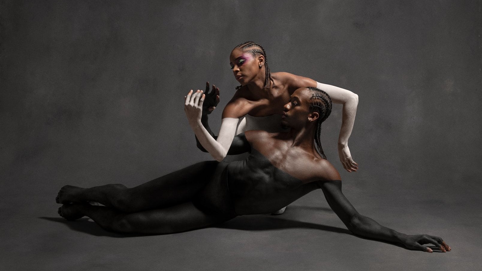Deux danseurs avec de la peinture  noire et blanche tenant une pose