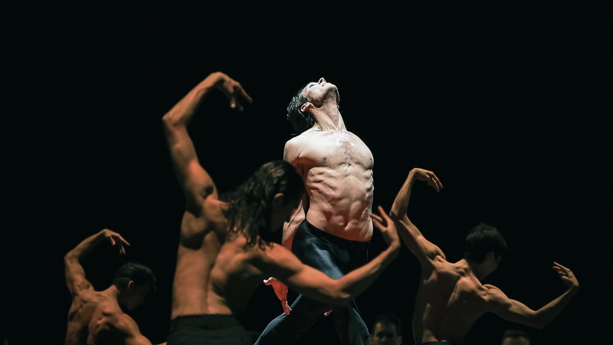 topless dancer on a stage, in the center of a circle of dancers