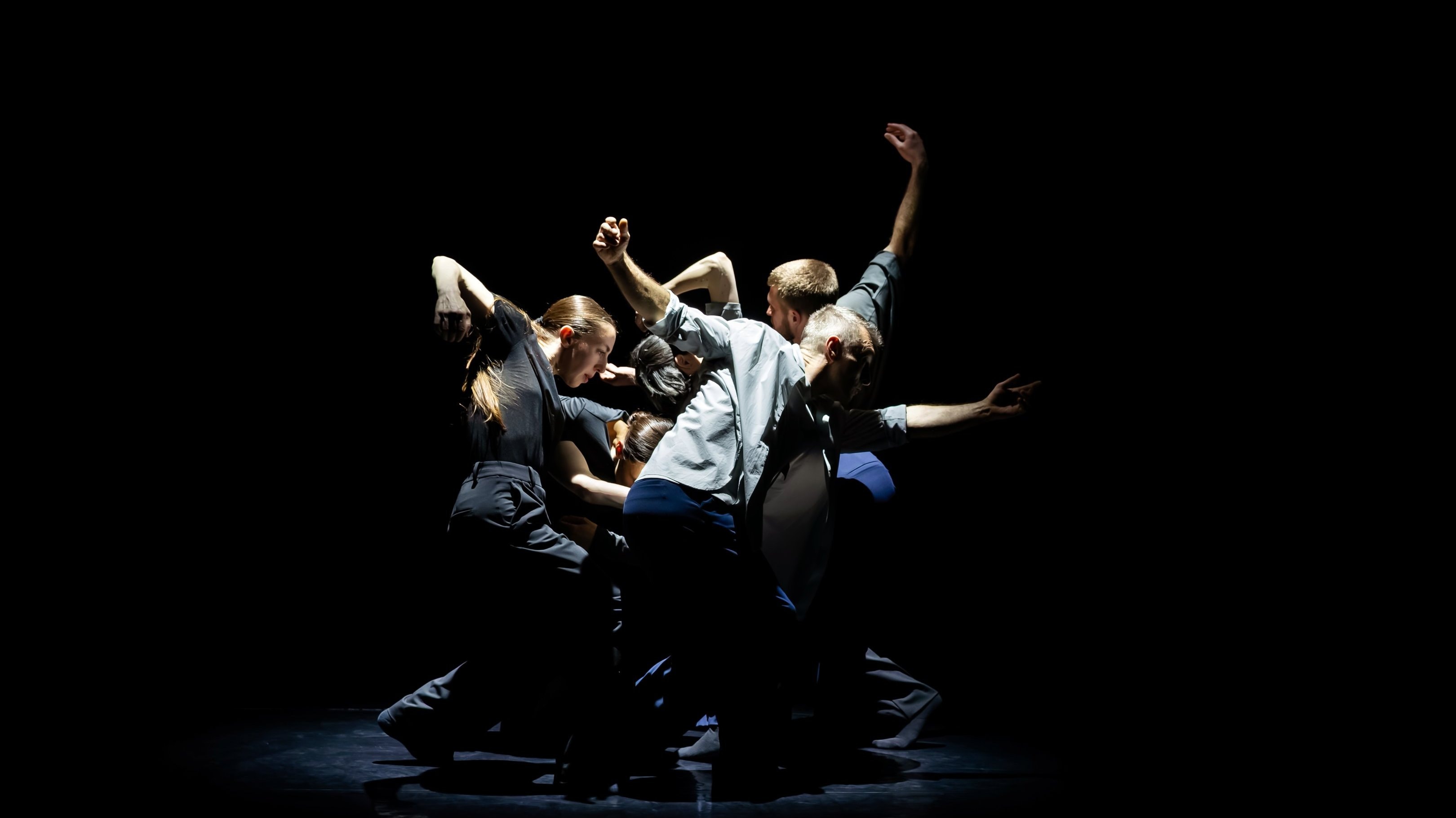 group of dancers in dynamic poses on a dark stage