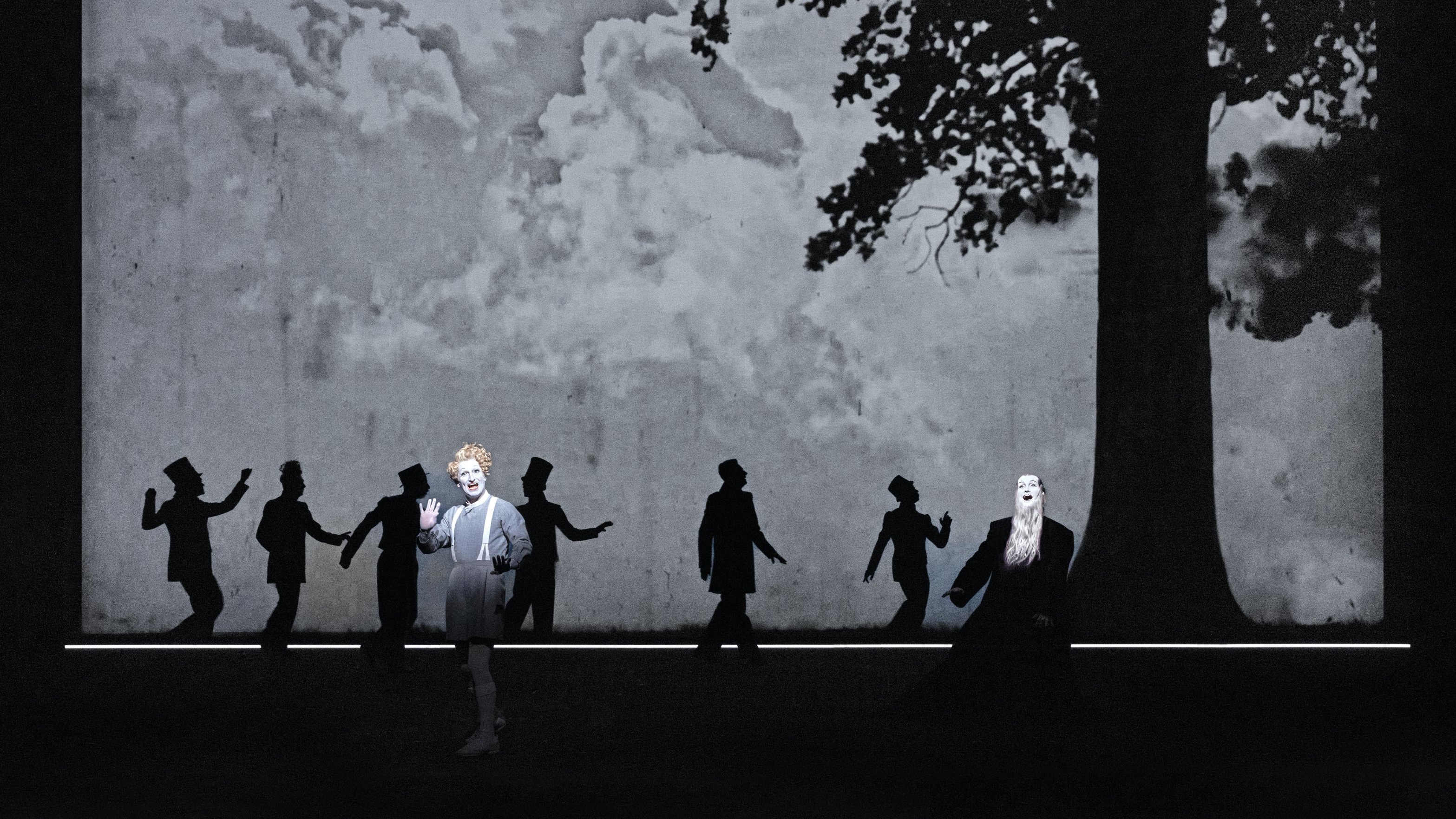 Dancers on a stage with a dark background and a tree