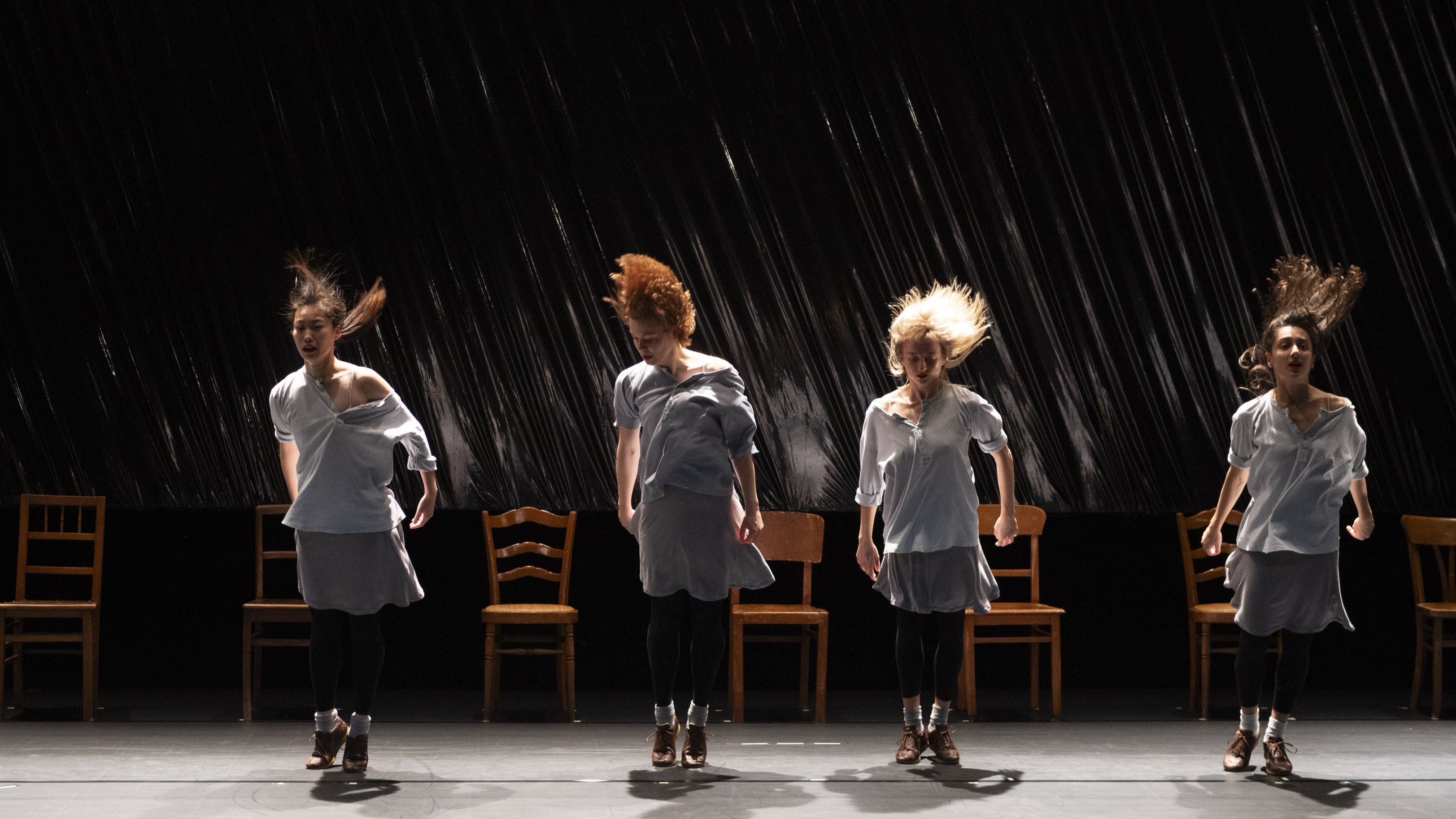 4 dancers standing in front of chairs 