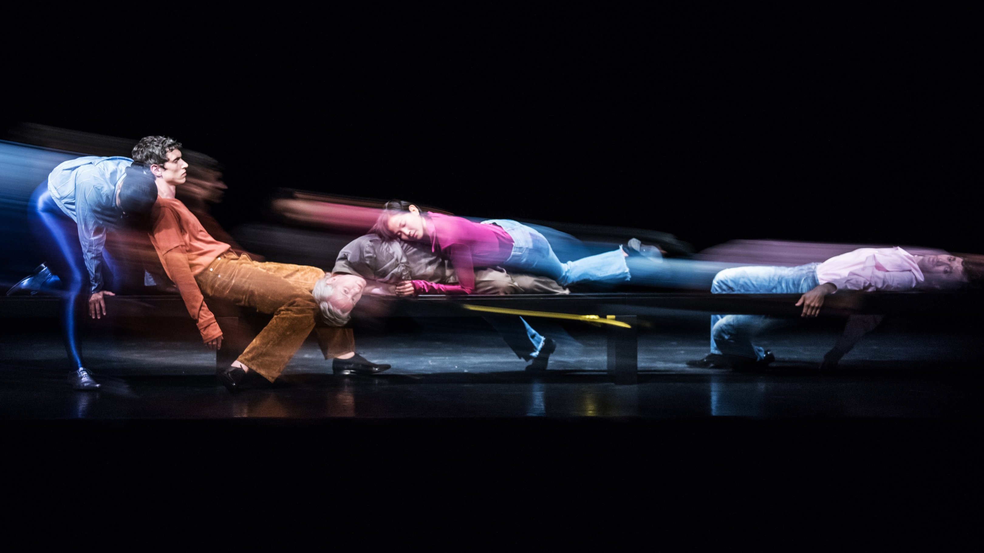 Danseurs assis les uns sur les autres dans des tenues colorées