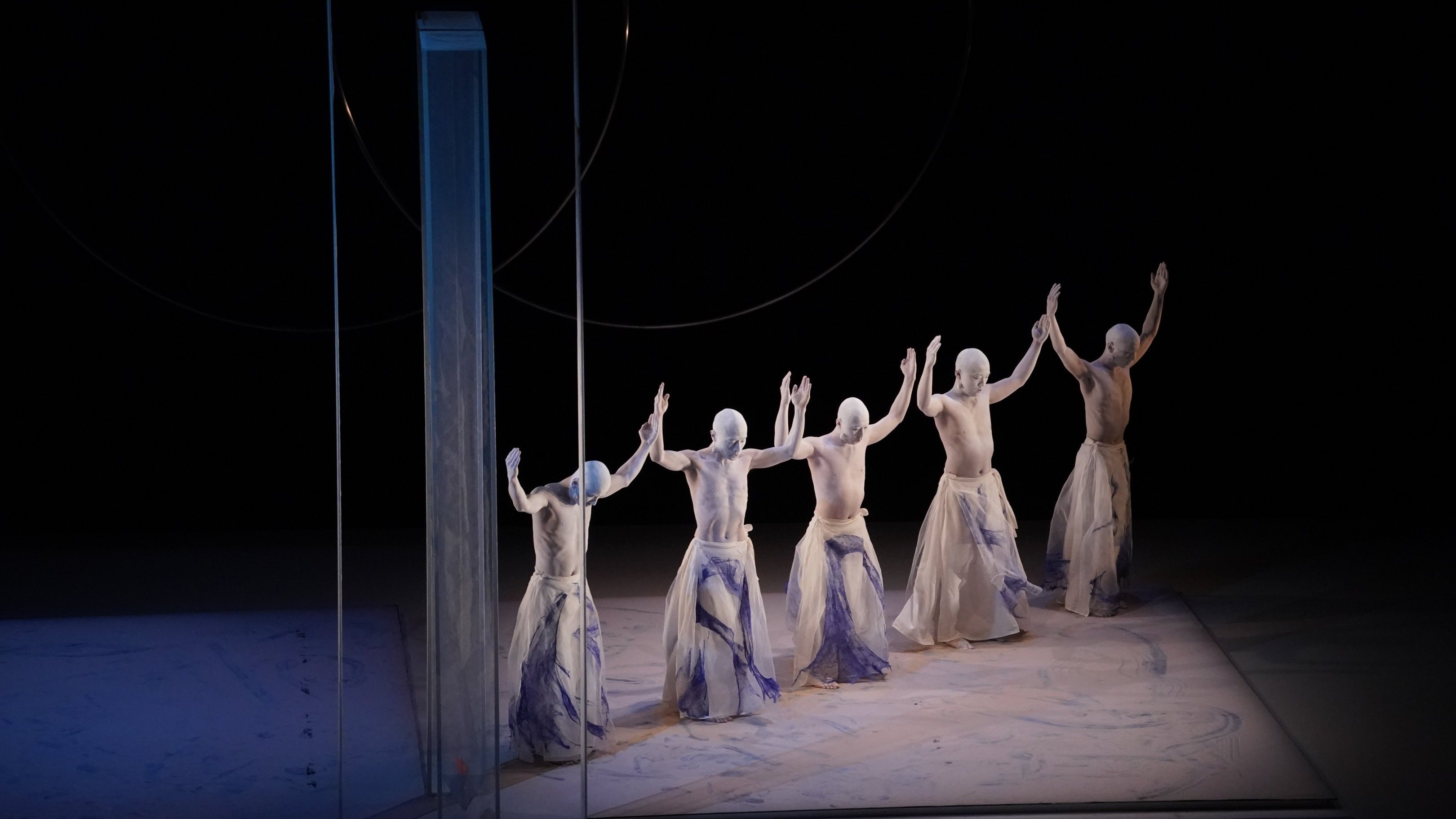Danseurs alignés portant leurs bras vers le haut. 