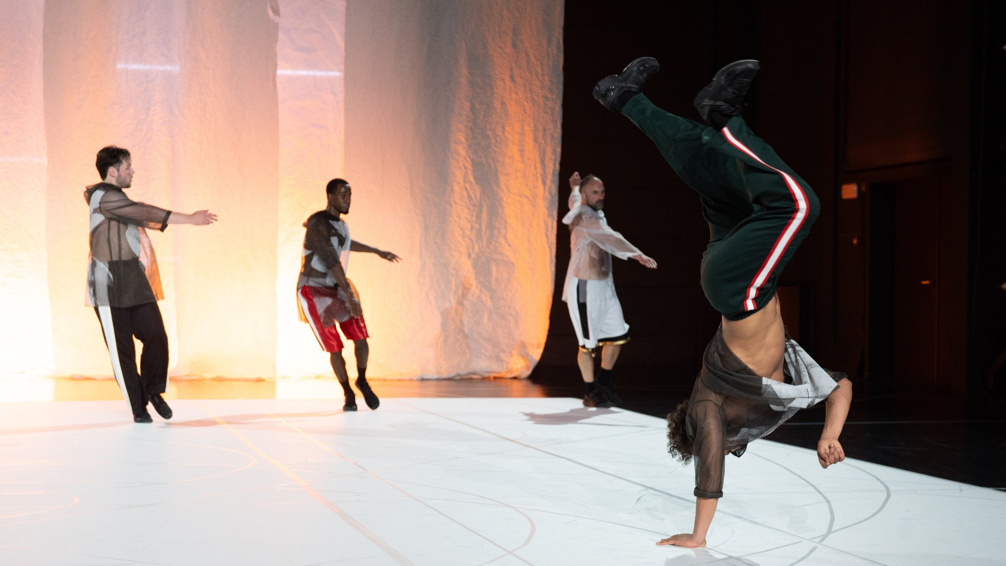 3 danseurs alignés en arrière plan et un breakdancer au premier plan