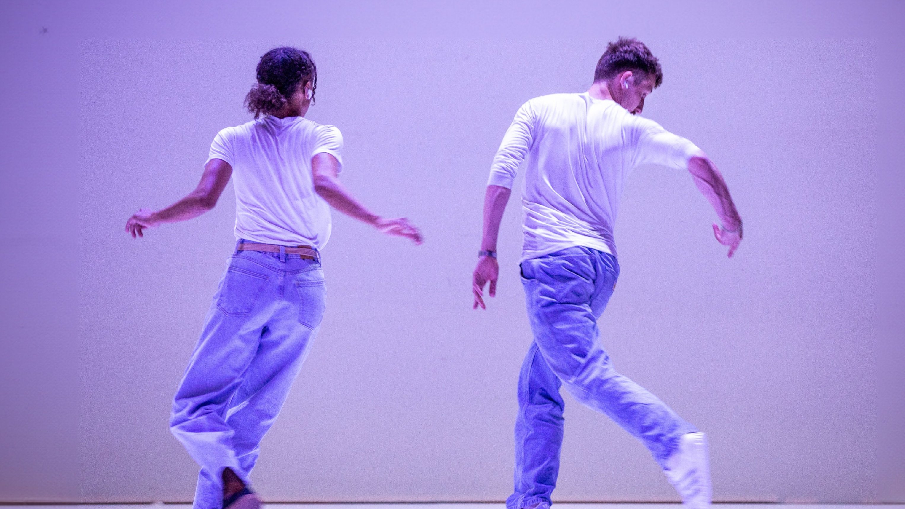 Danseurs en mouvement de dos, avec un fond mauve. 