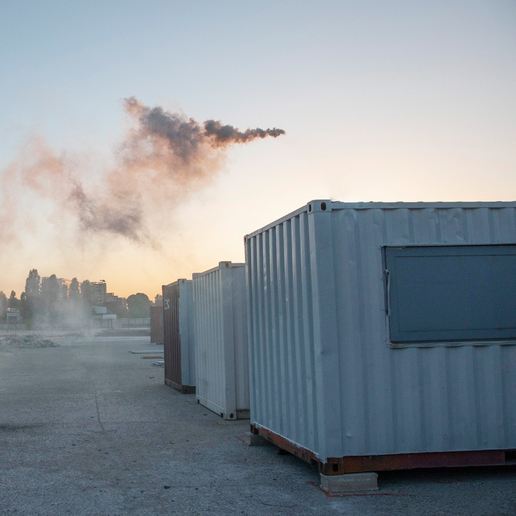 Conteneurs sur sol en béton, gravas et fumée