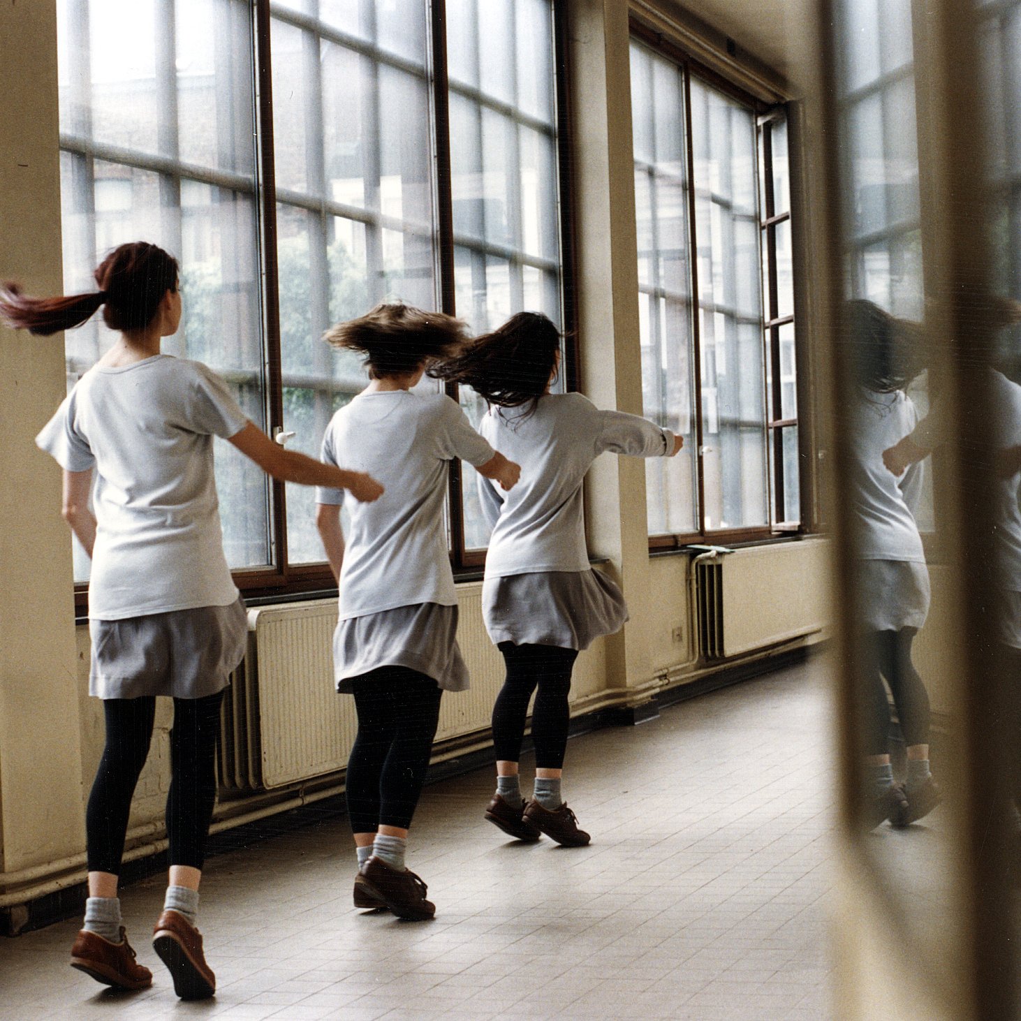 3 filles dansant en ligne devant un fênetre