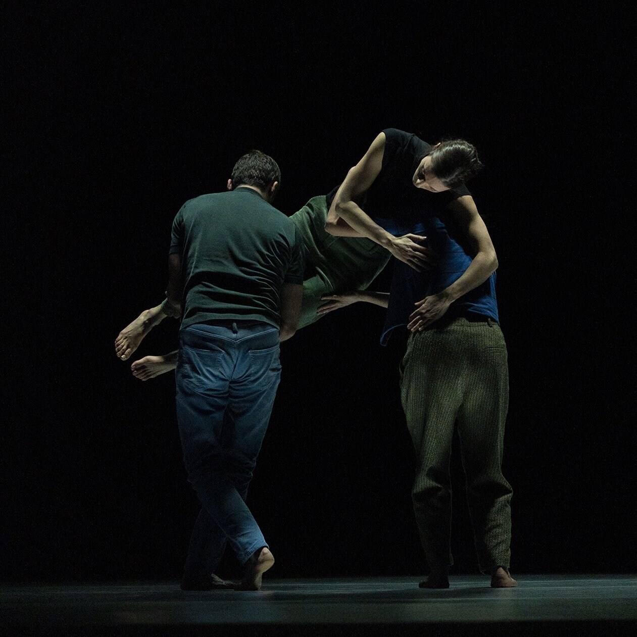 两位舞者面对舞台背景，而另一名舞者则转向观众