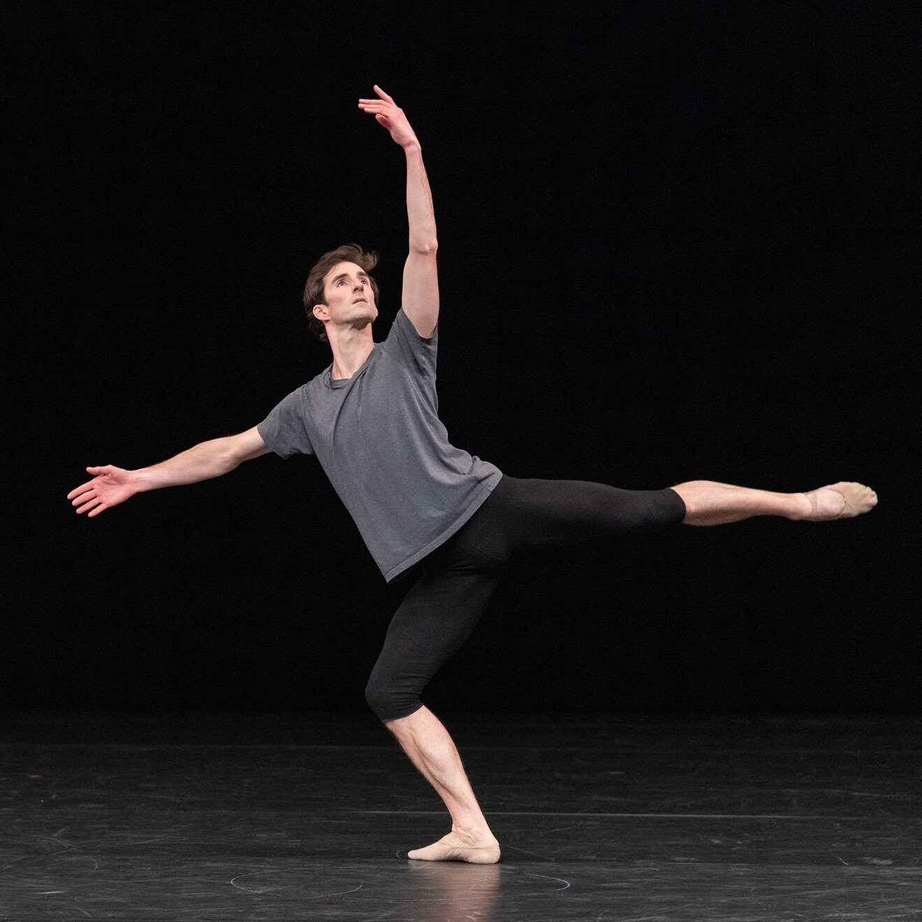 un danseur en arabesque regardant vers sa main lévée