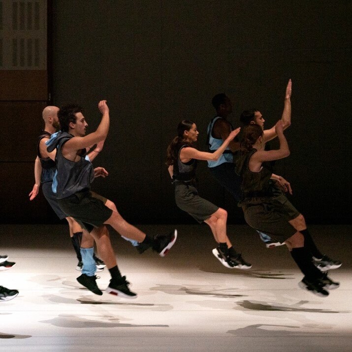 Dancers on stage all jumping at the same time with lifted arms