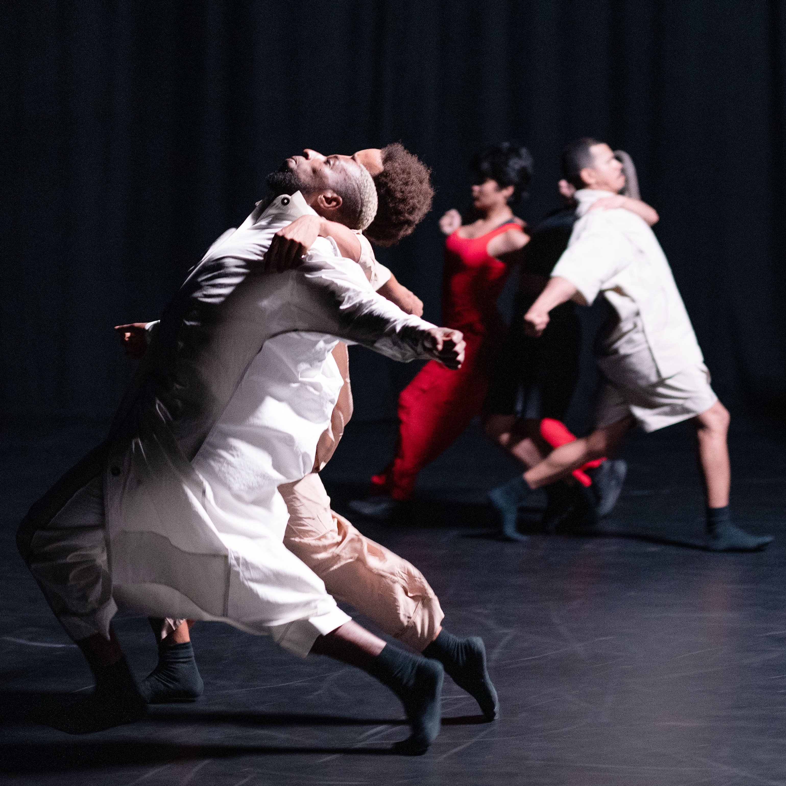 Dancers dressed in white, leaning back