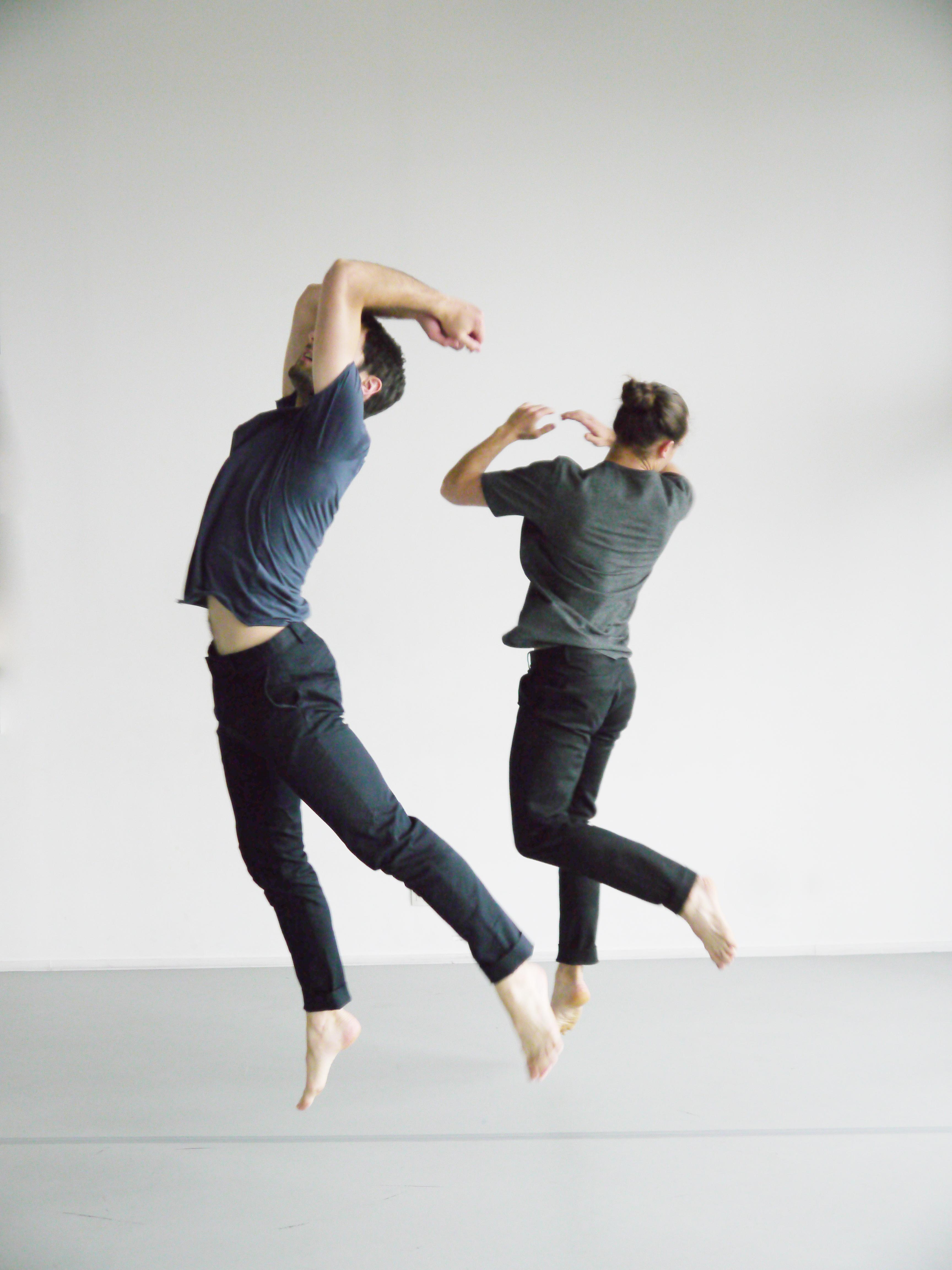 Two men jumping in a grey room