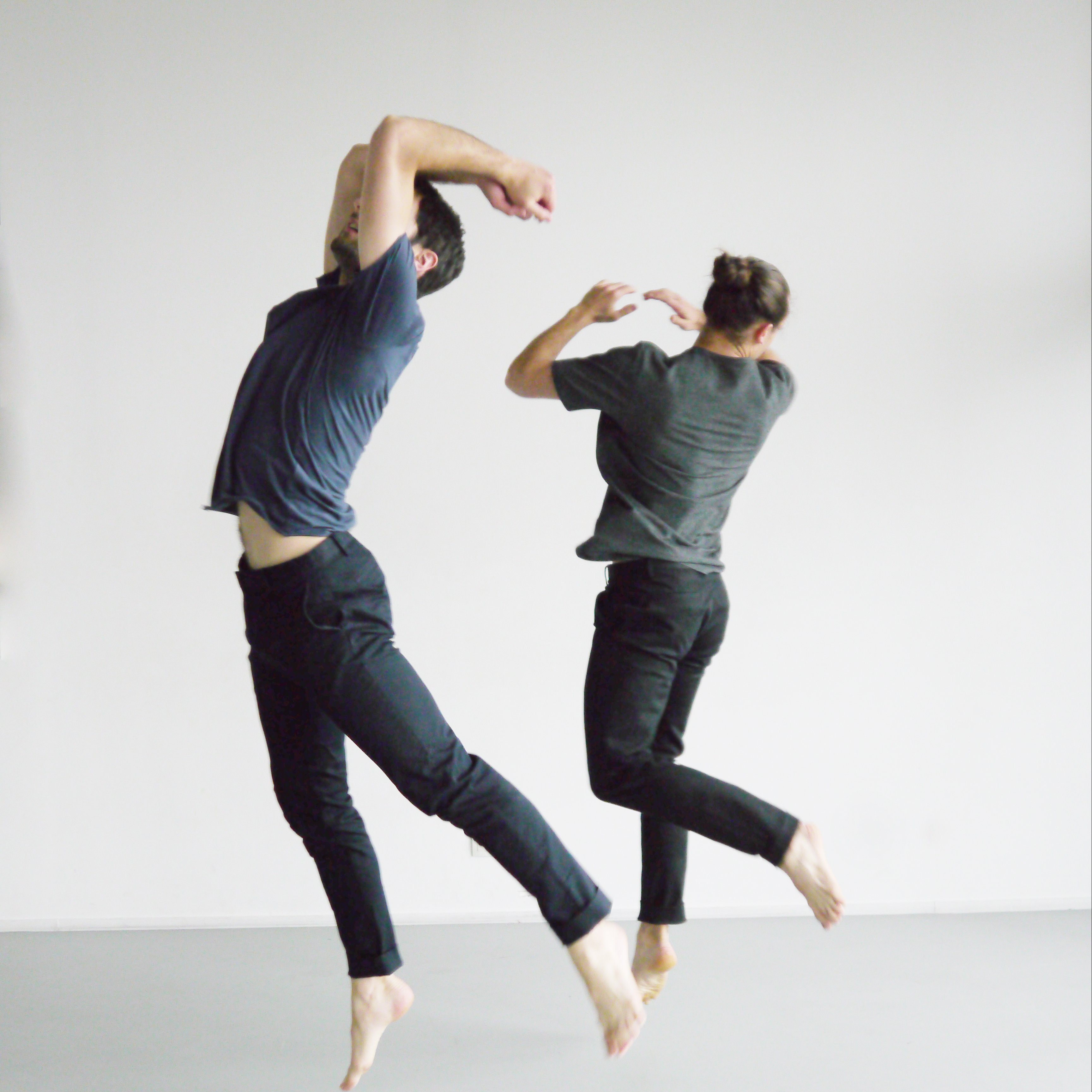 Two men jumping in a grey room