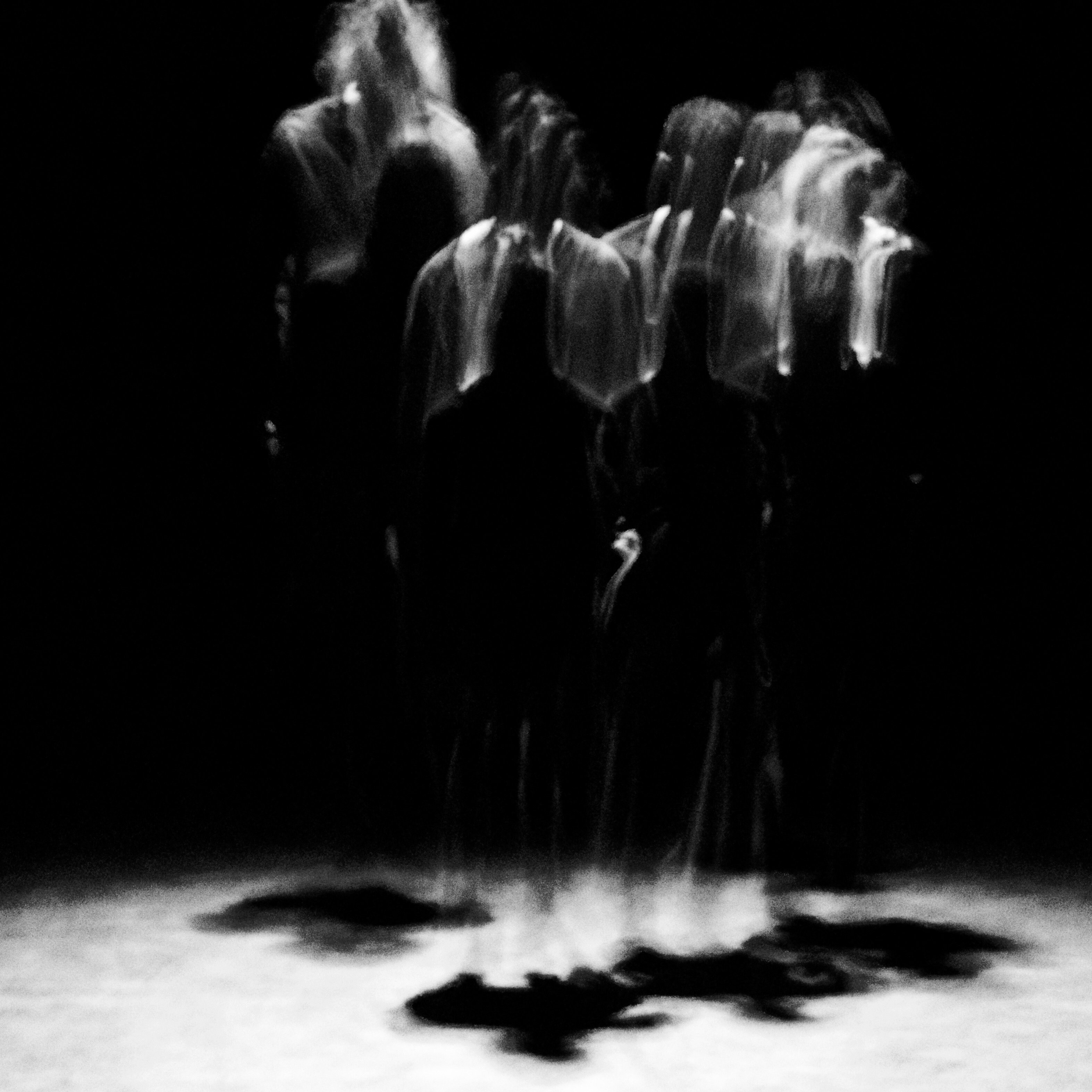 Blurry silhouettes dancing in the dark, illuminated by a ray of light
