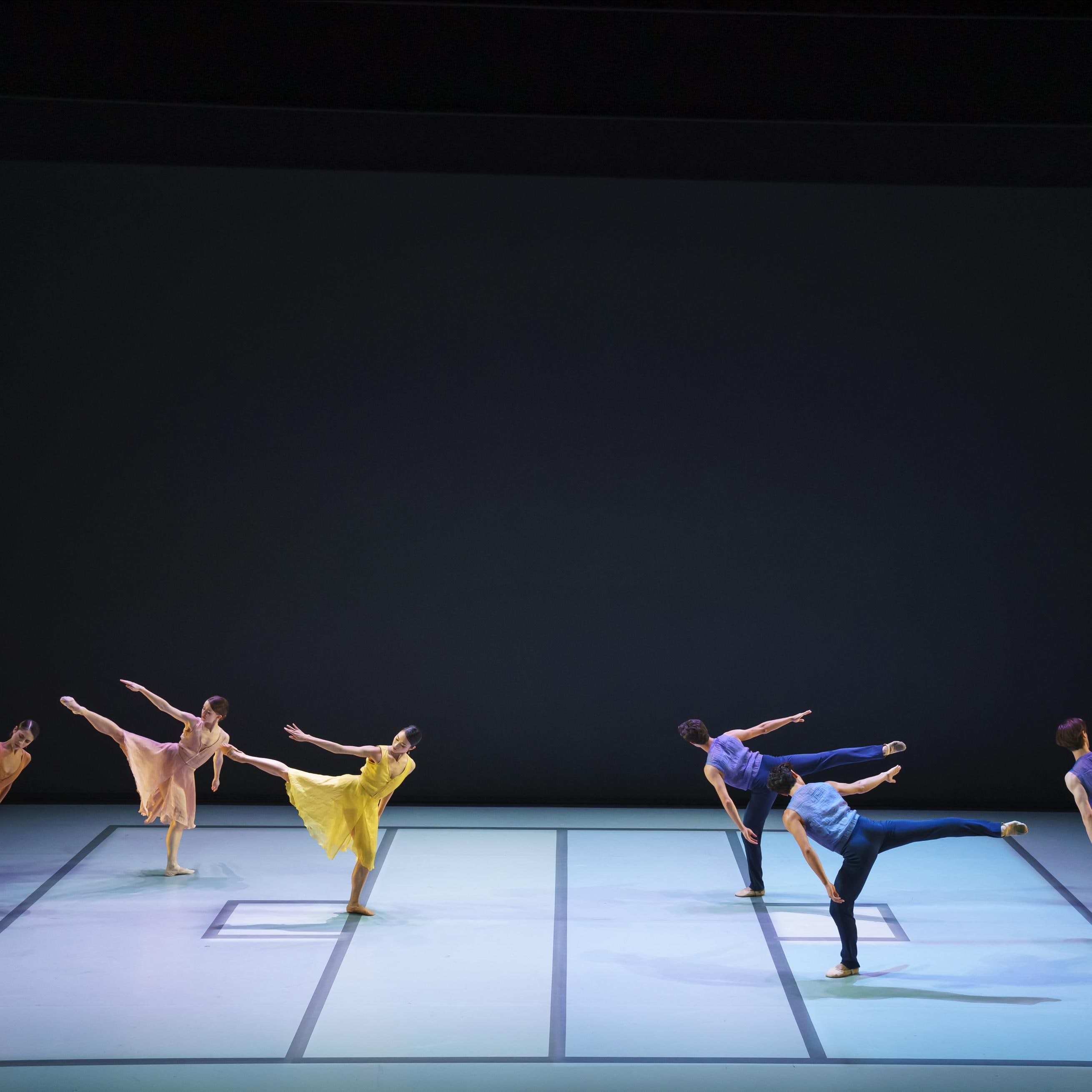 Danseurs vêtus de couleurs vives, avec le bras droit et la jambe droite levés.