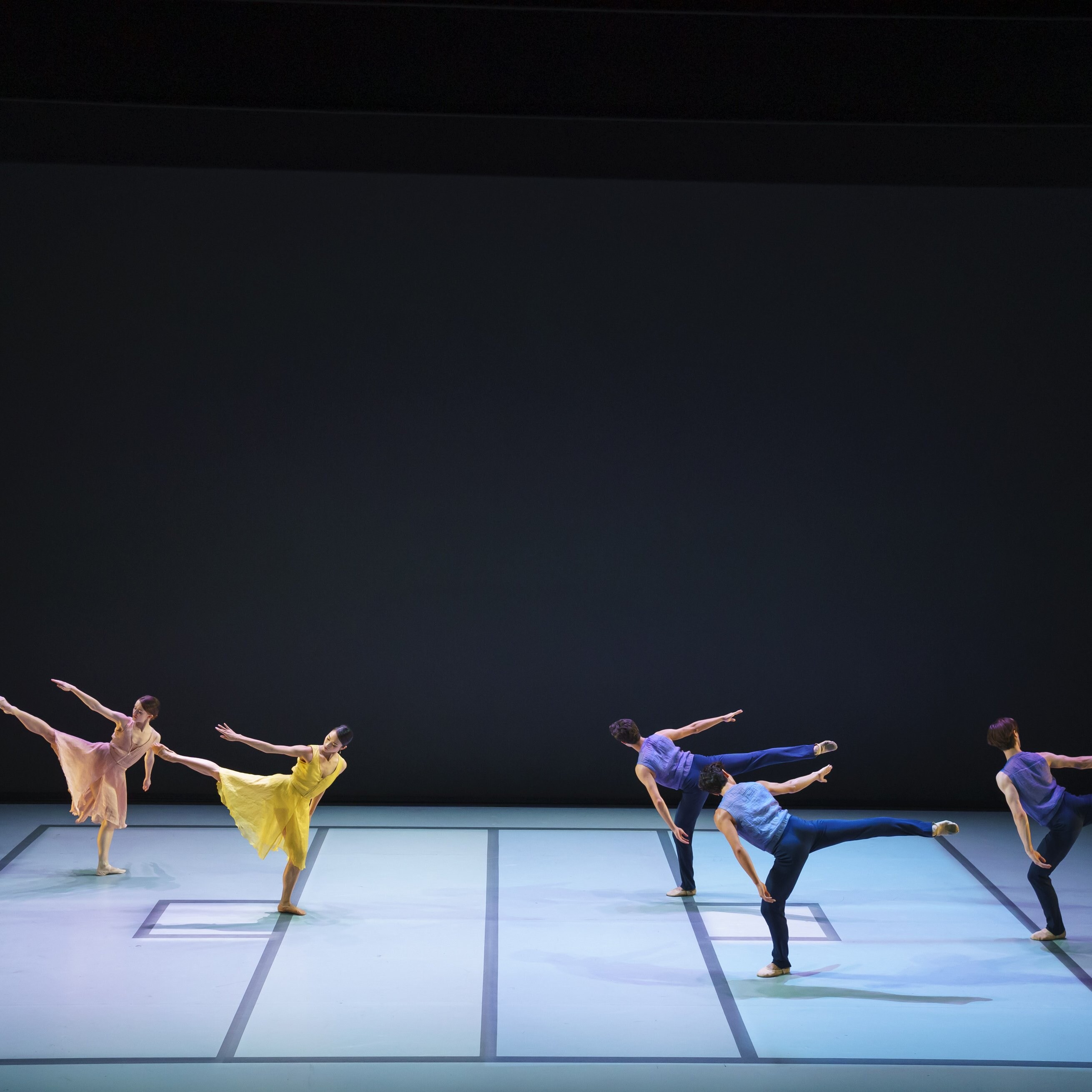 Dancers wearing bright colors, with right arm and leg raised.