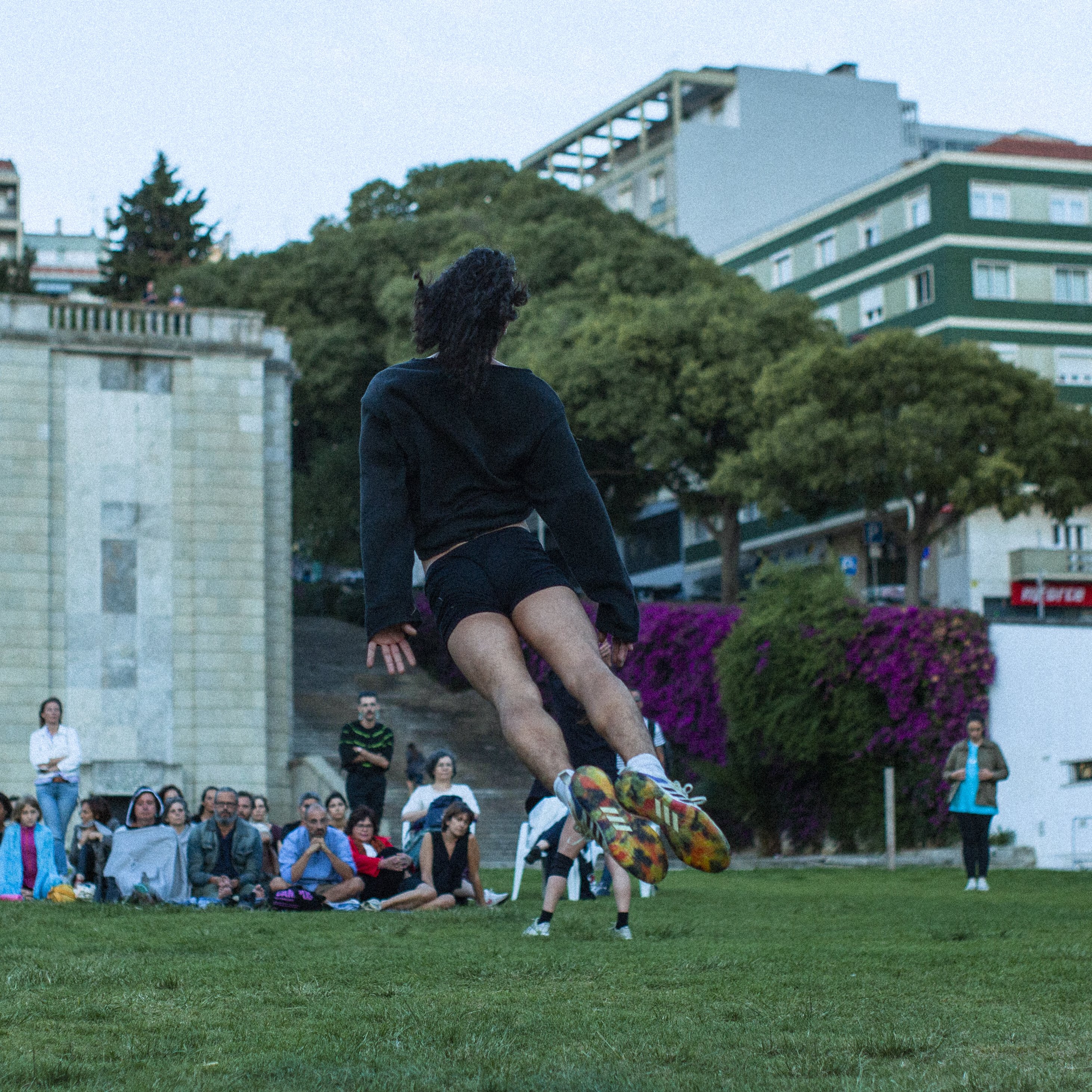a dancer jumping in a garden, facing away
