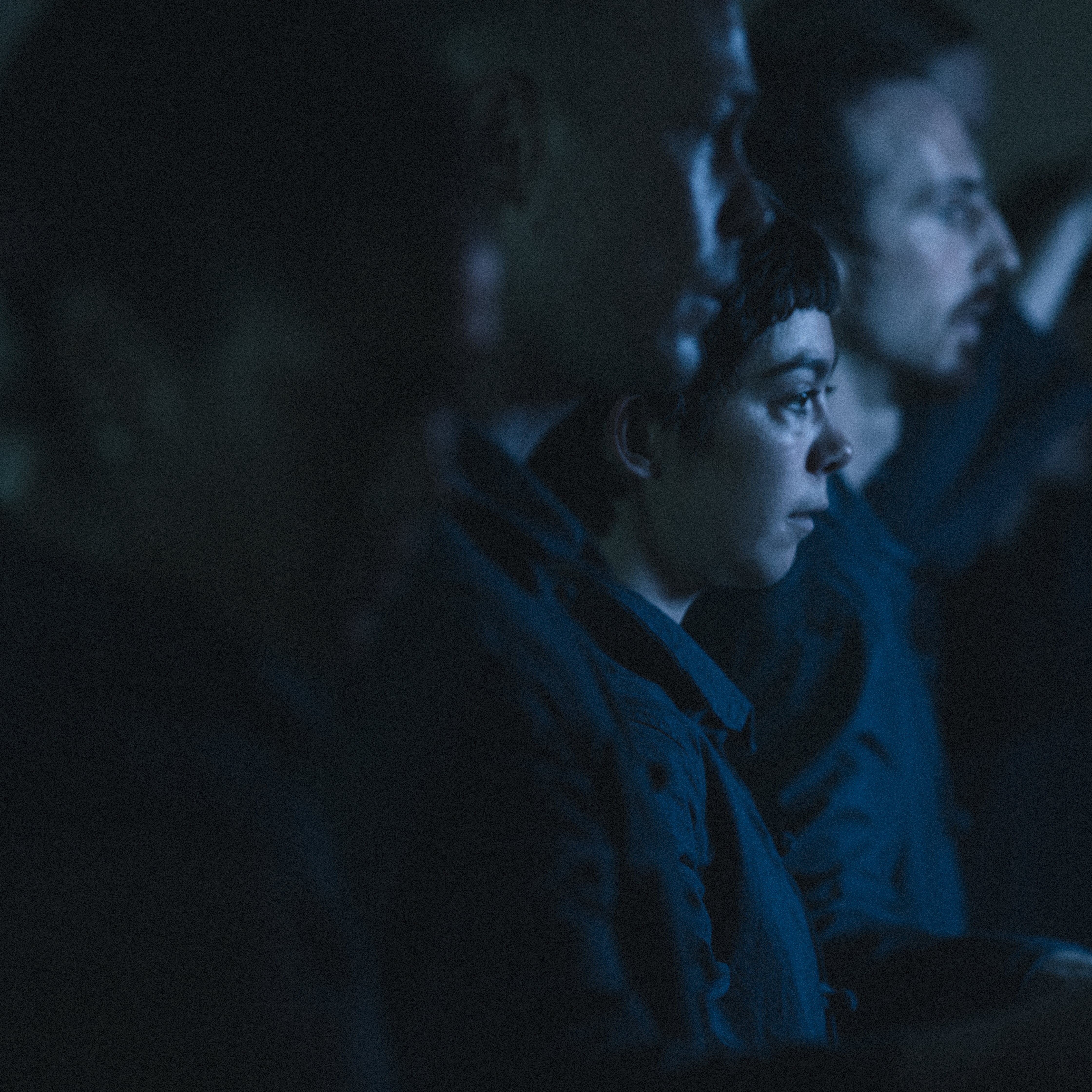 dancers seen in profile, in a dark room with a navy blue light