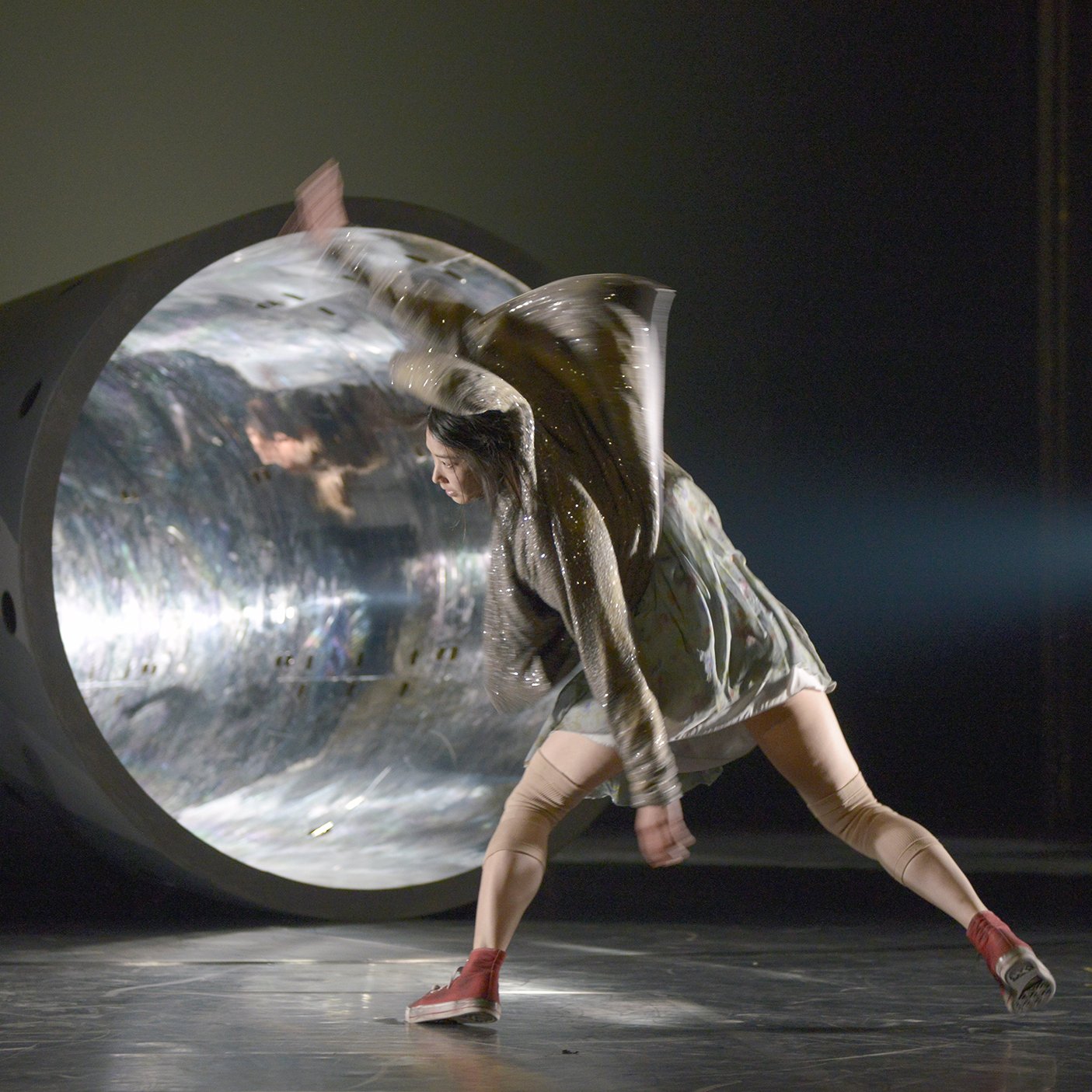 Woman dancing in front of a tunnel illuminated by a ray of light