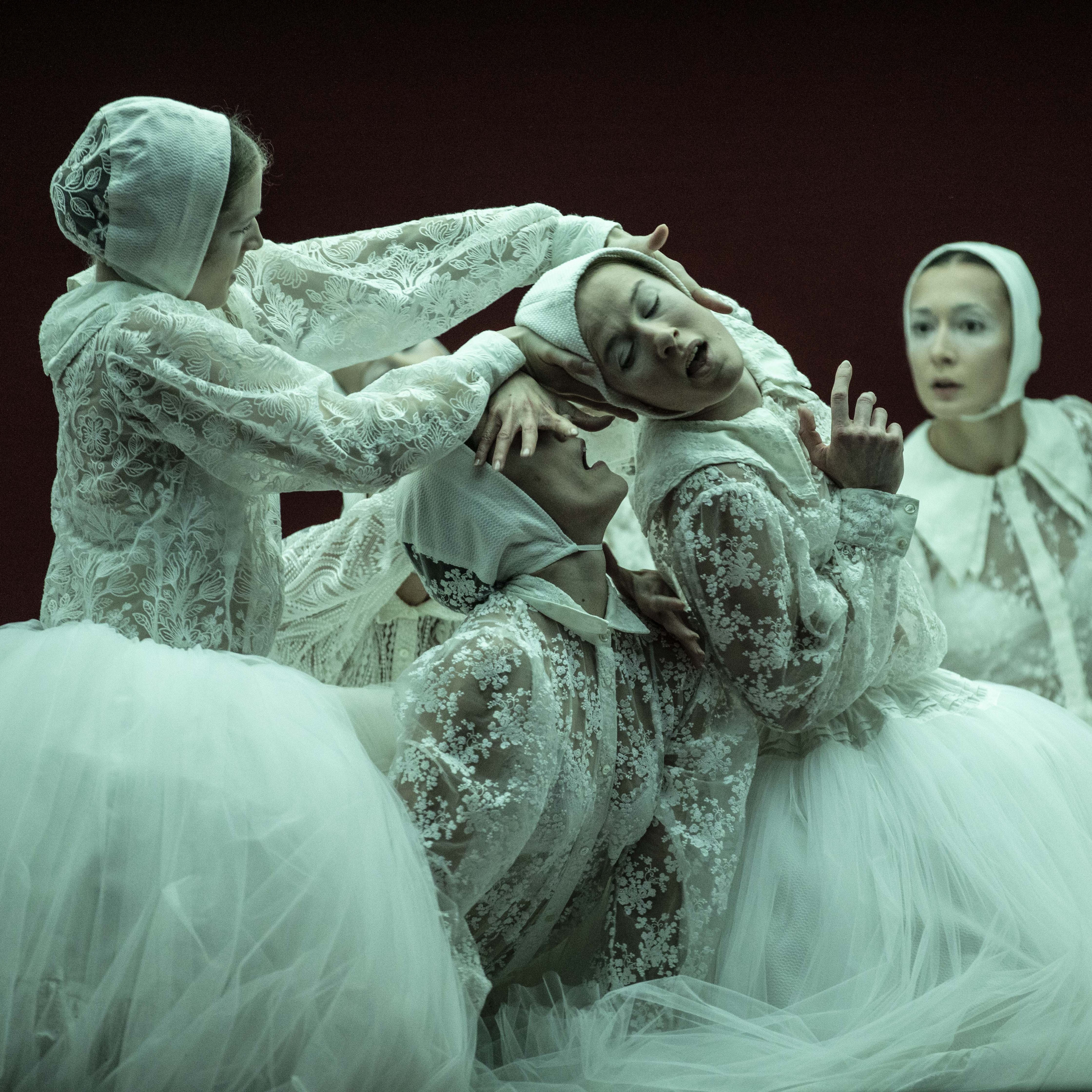 Dancers dressed in tutus and white lace tops bending over each other
