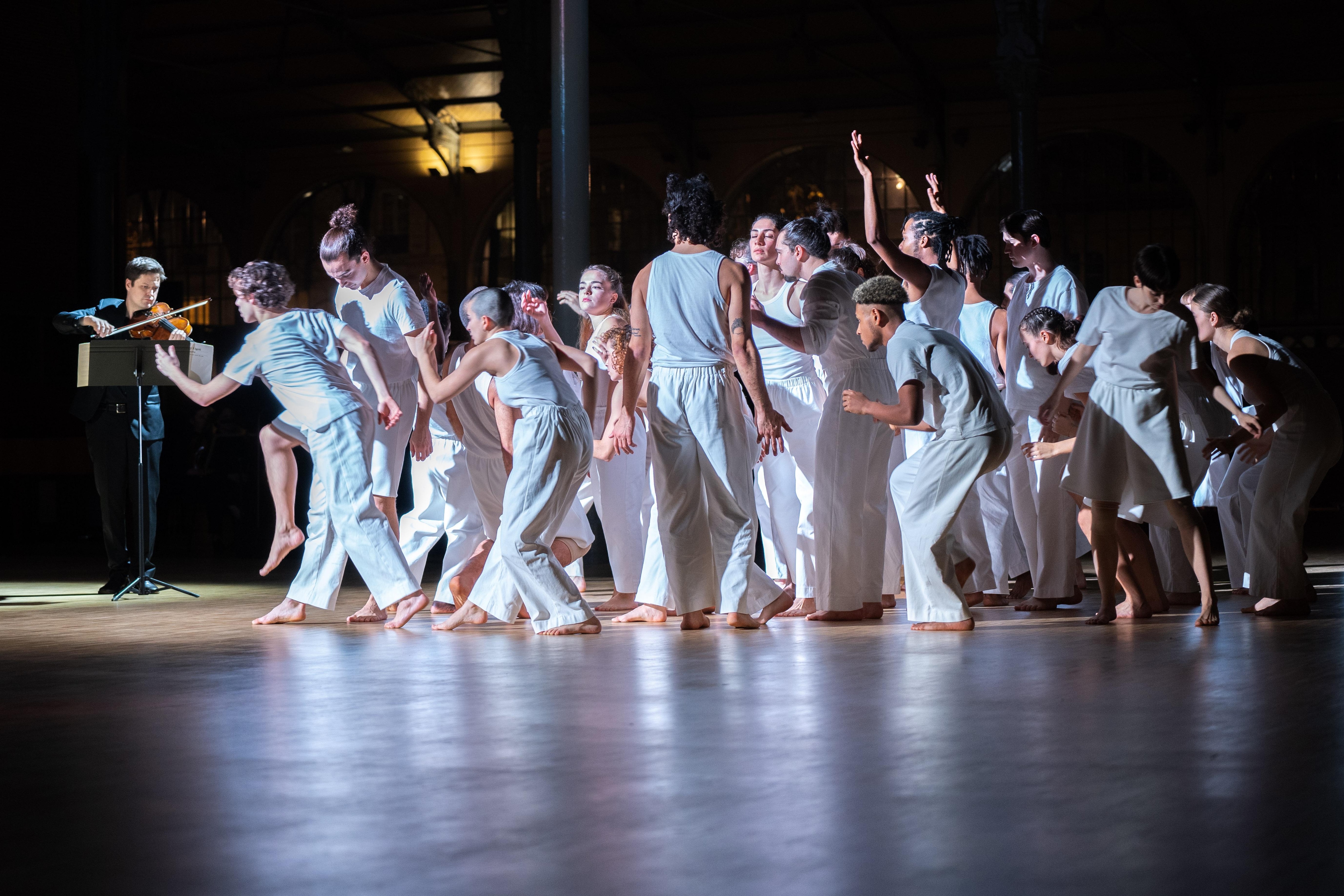 Danseurs debout en tenue blanche, agroupés, réalisant des mouvement désynchronisés