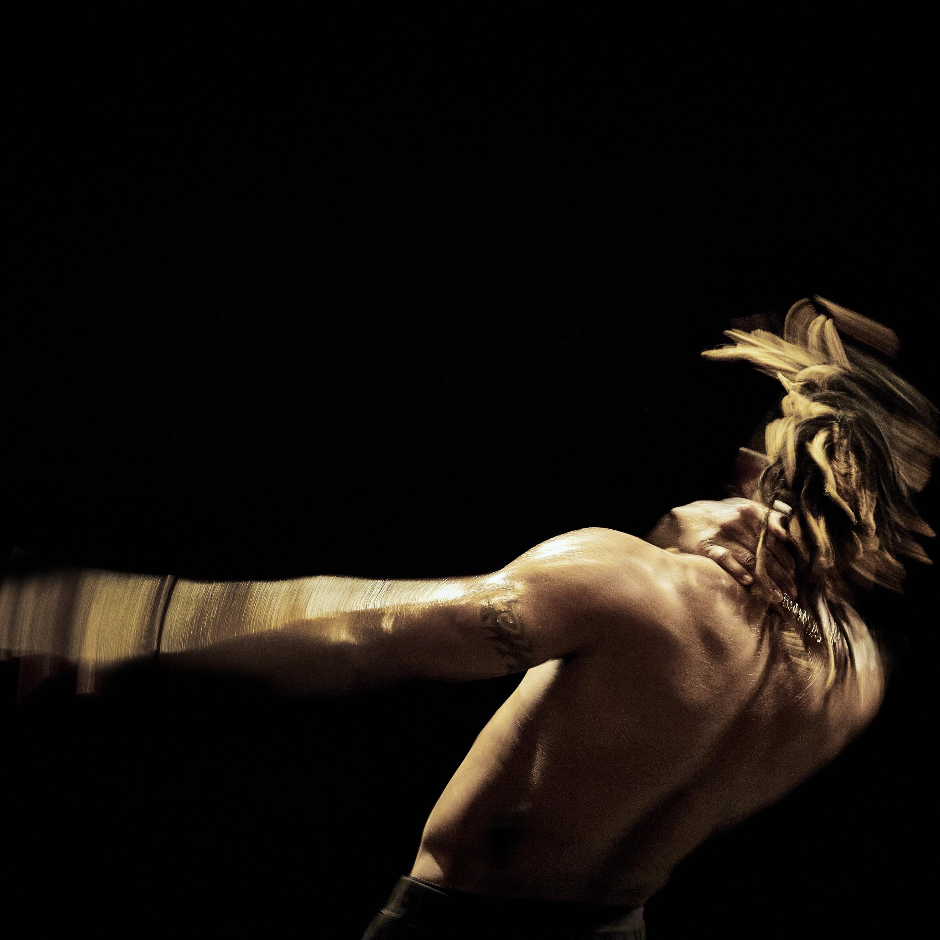 Michel « Meech » Onomo from the back, shirtless and moving in a black background