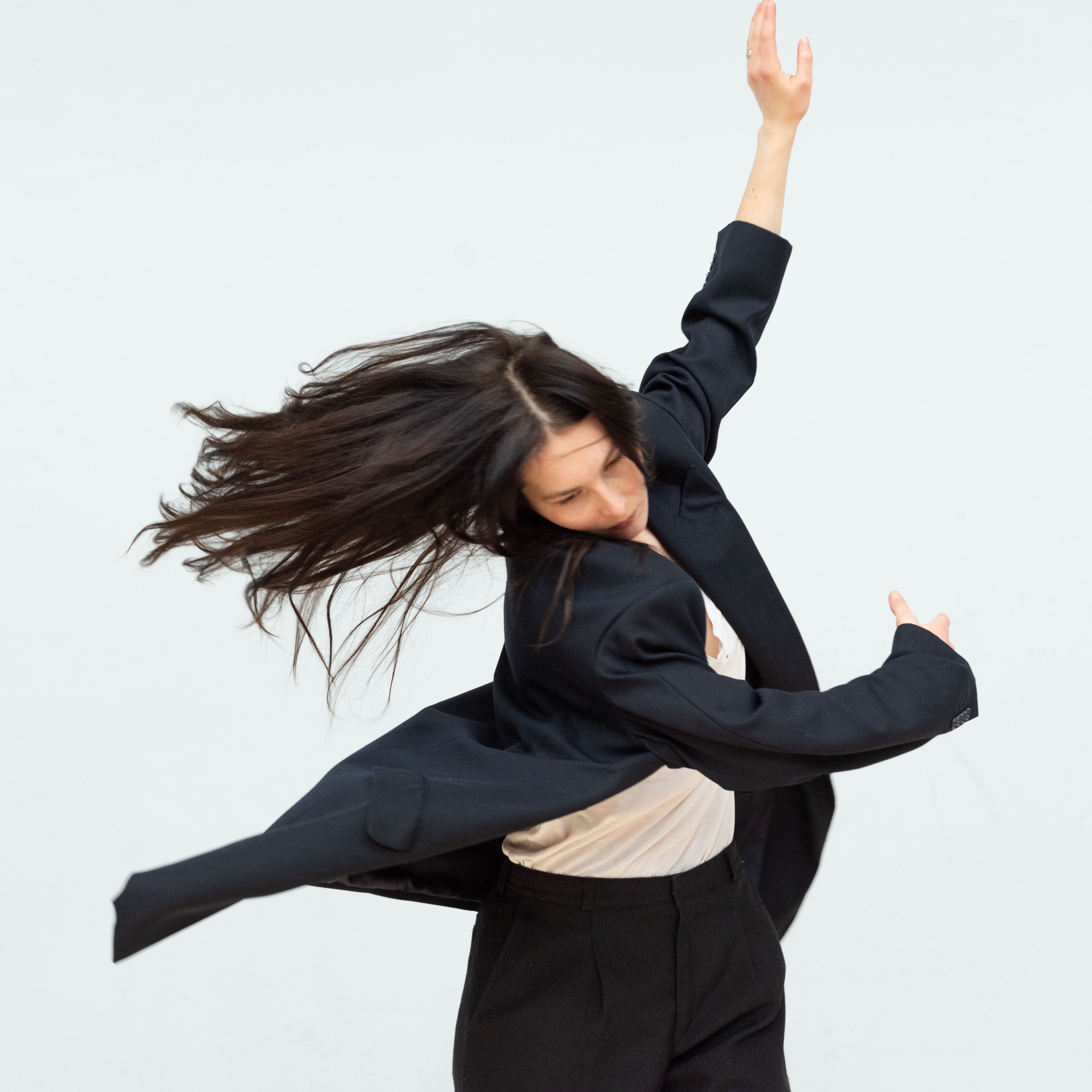A dancer performing Anne Teresa De Keersmaeker’s Sand/Encore 1Été, her arms in movement to her side