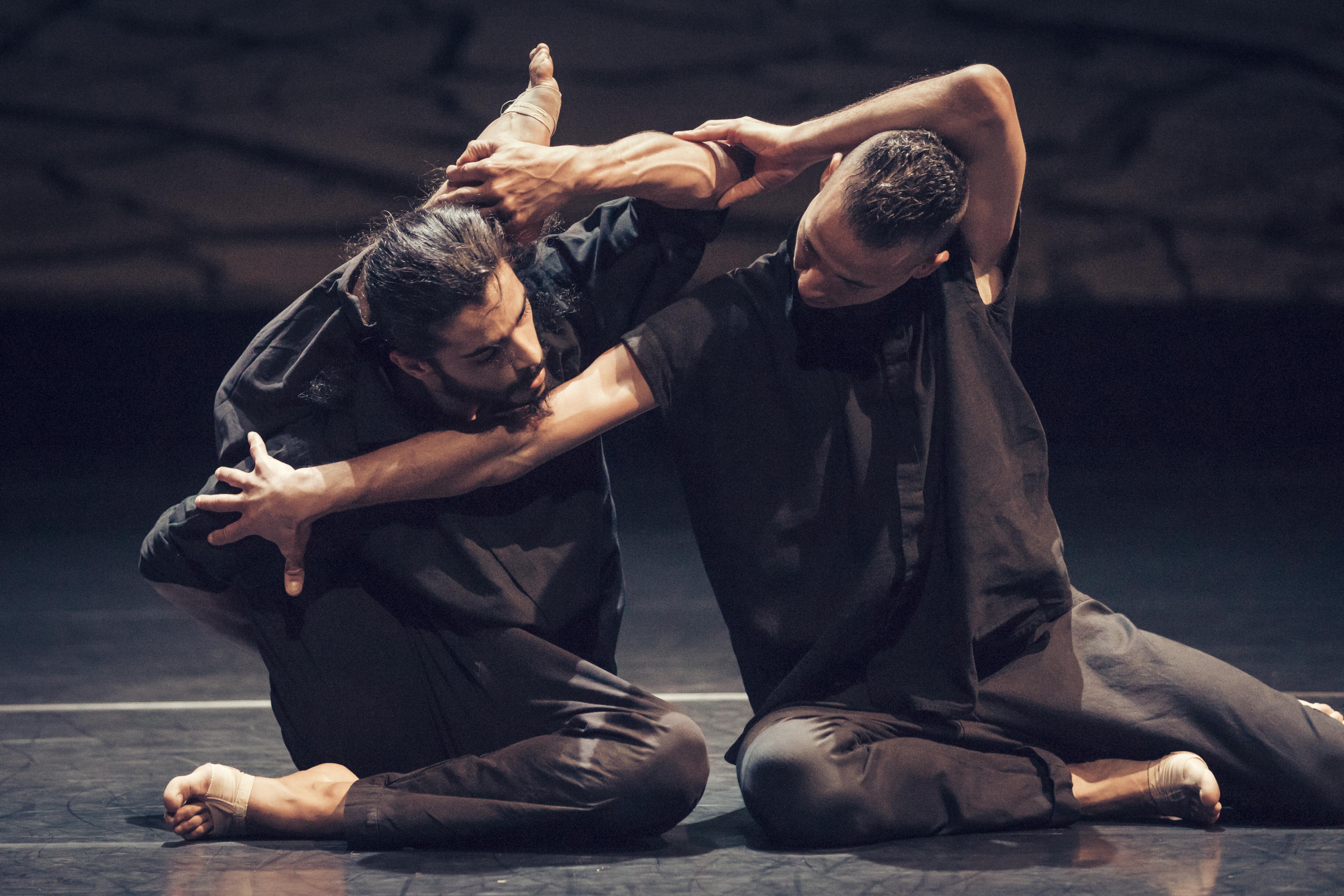 Deux danseurs vêtus de noir assis sur le sol