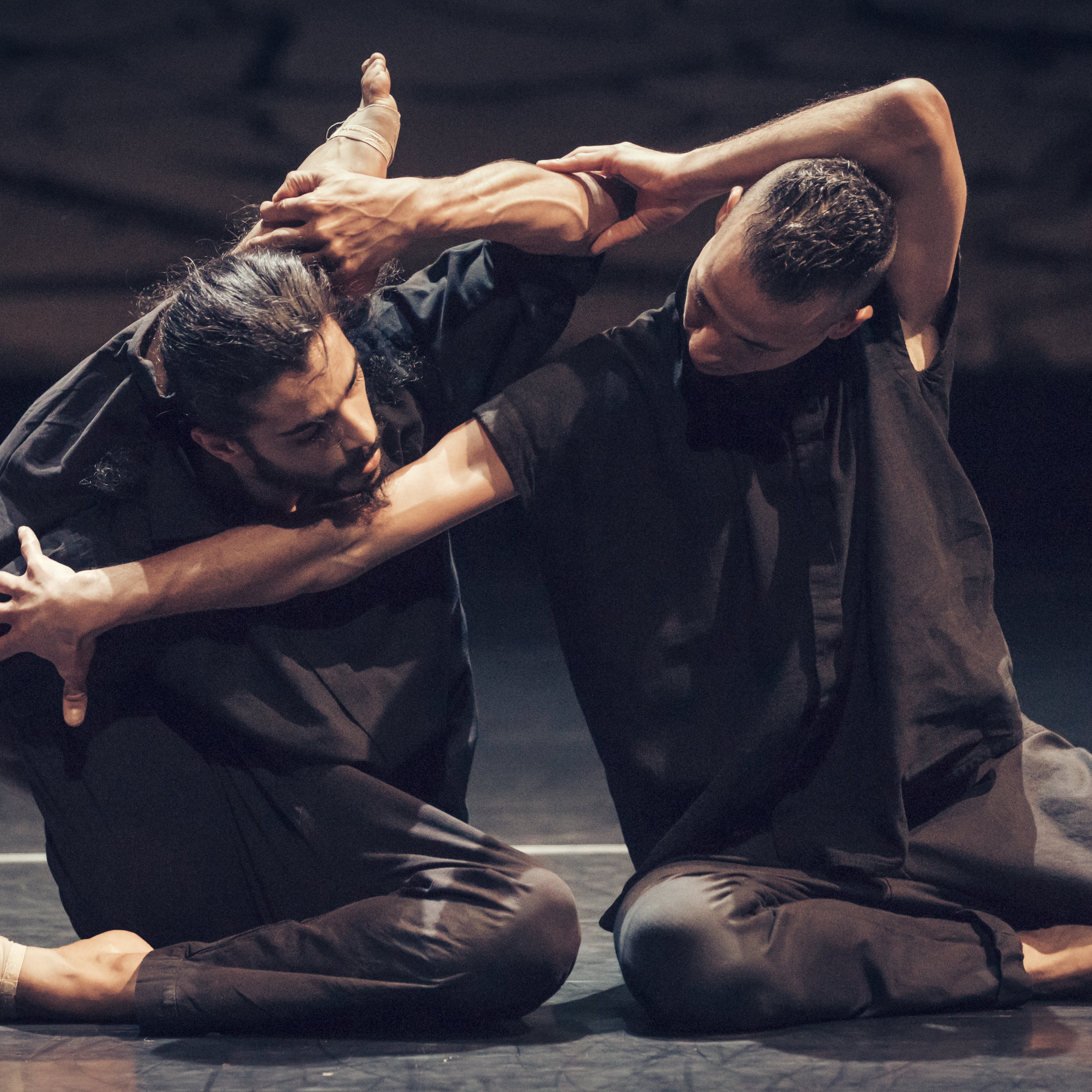 Dancers dressed in black sitting on the floor