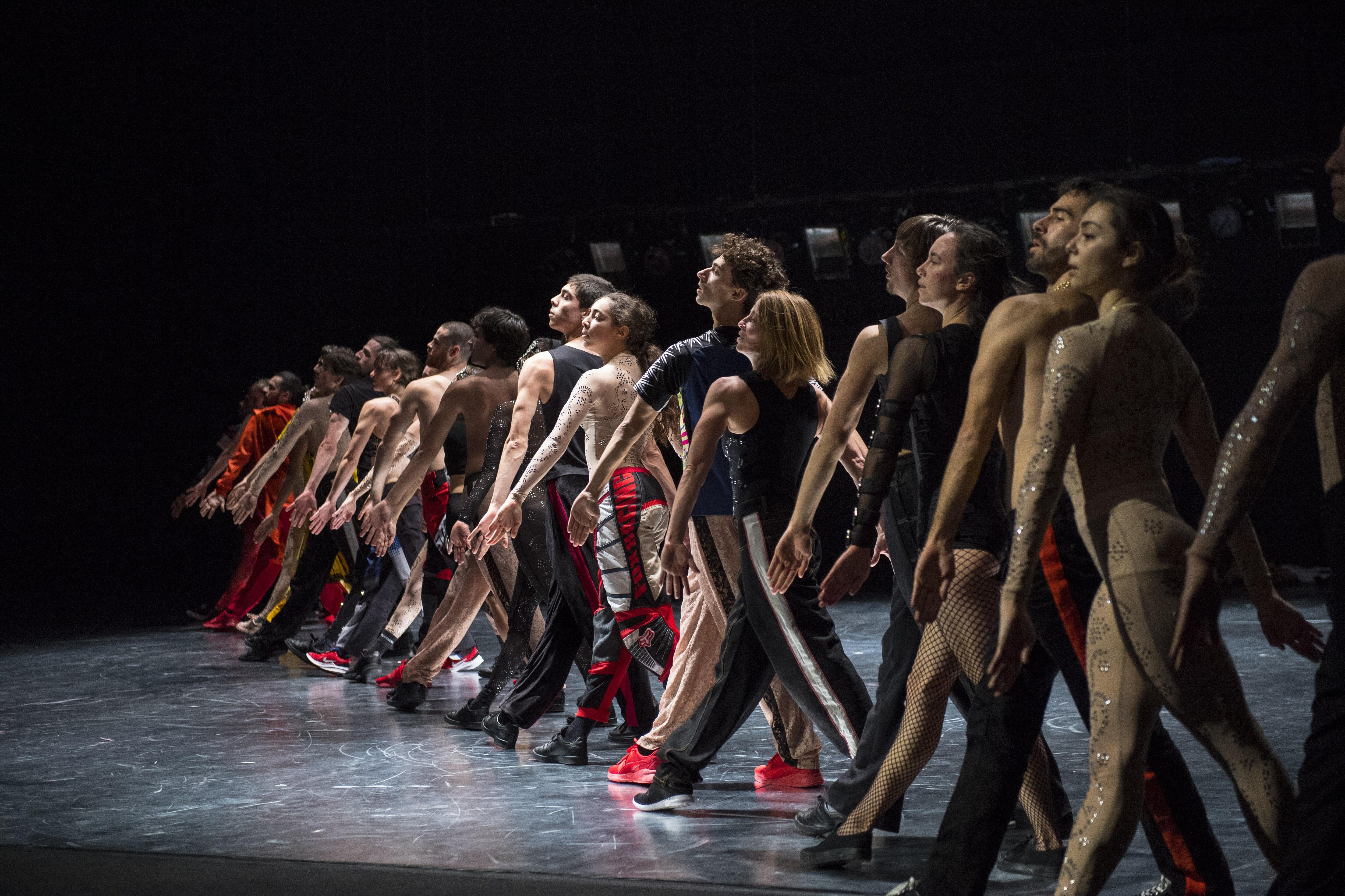 Dancers standing in a line with one leg forward, in Static Shot by Maud le Pladec