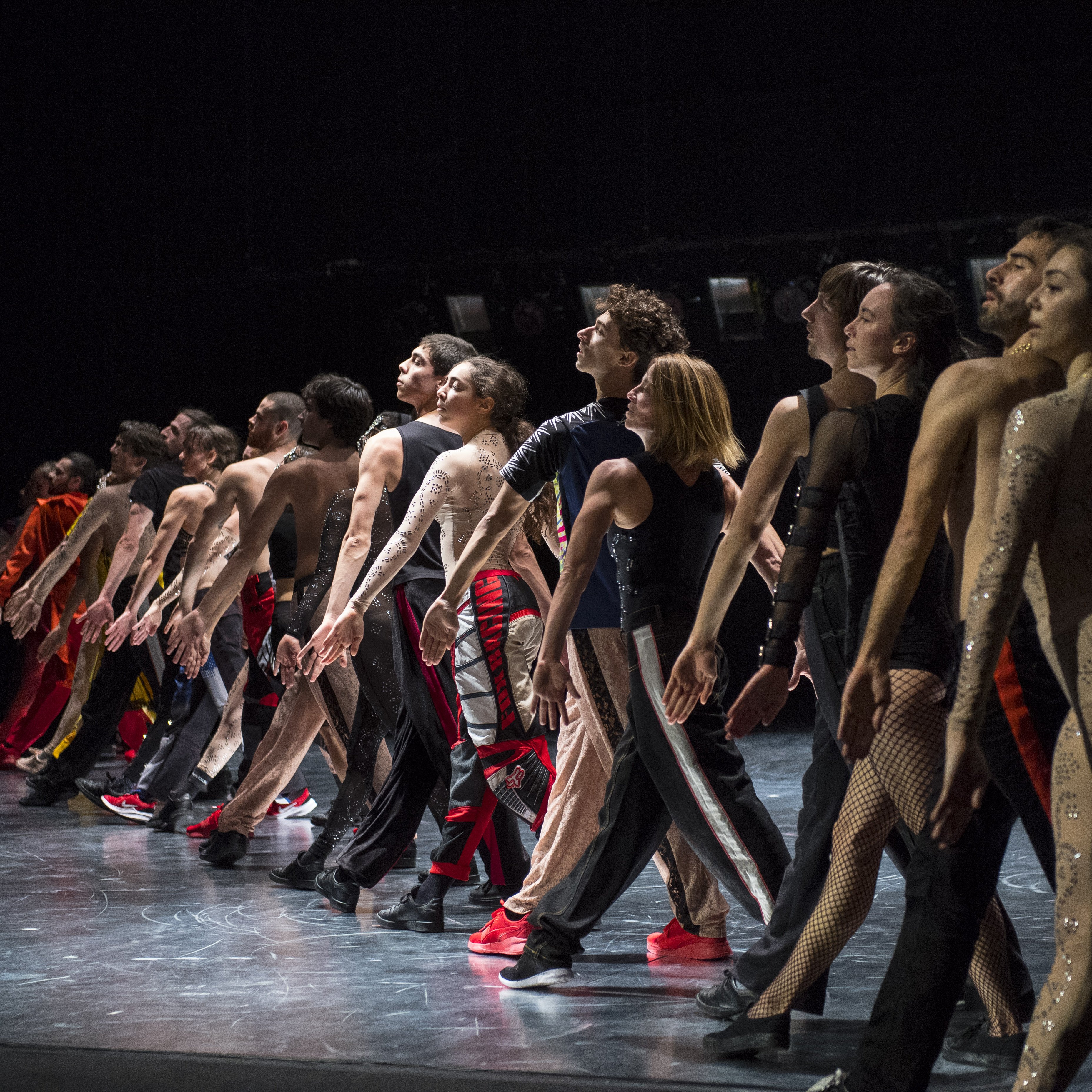 Dancers standing in a line with one leg forward, in Static Shot by Maud le Pladec