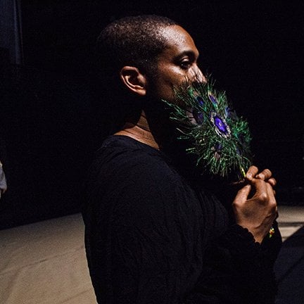 Danseur tenant un objet en plume devant le visage