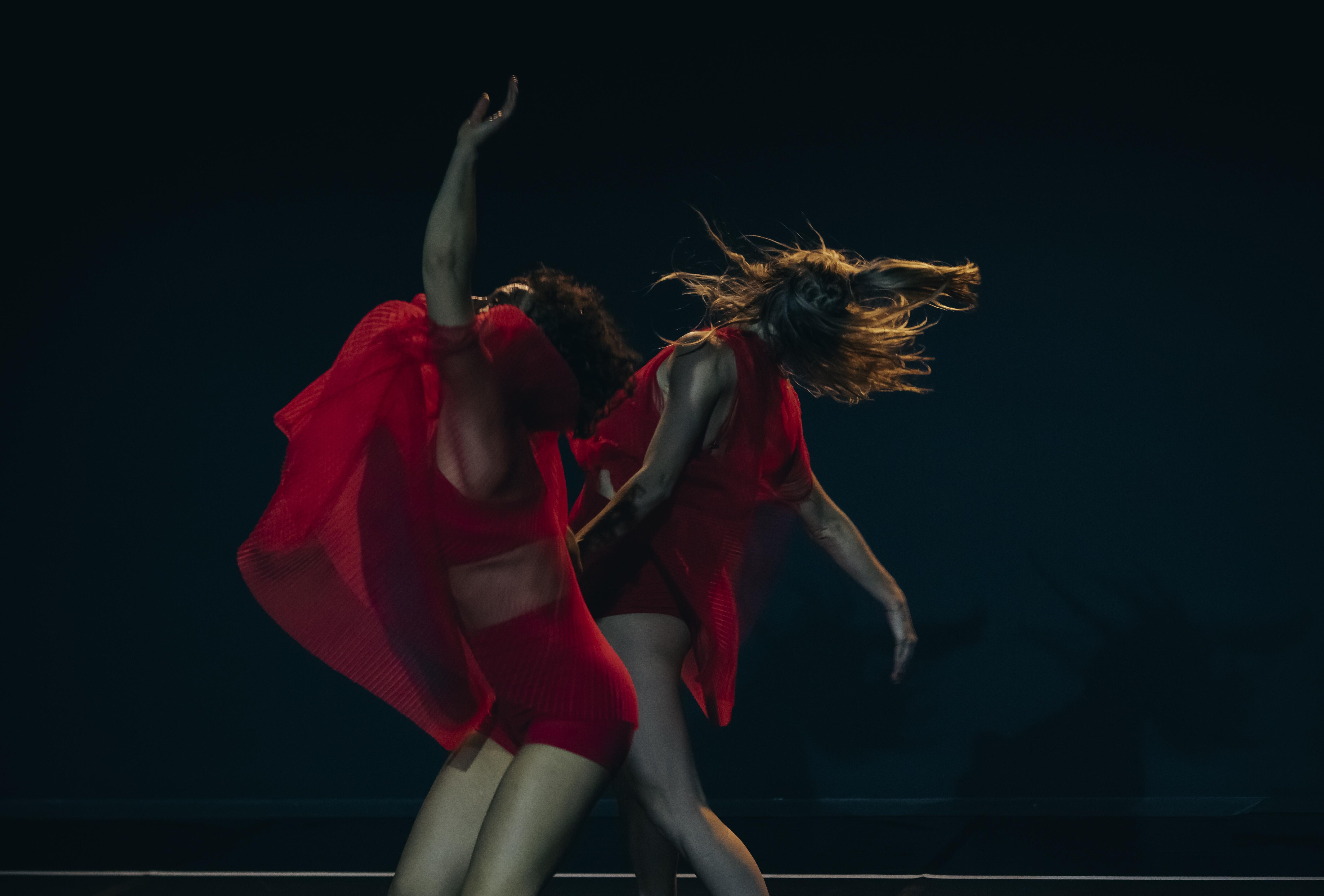 Two dancers in red in Lucy Guerin's How To Be Us.