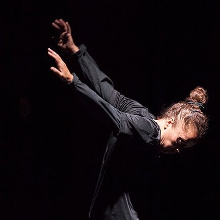 Danseuse sur fond noir, les bras vers l’arrière