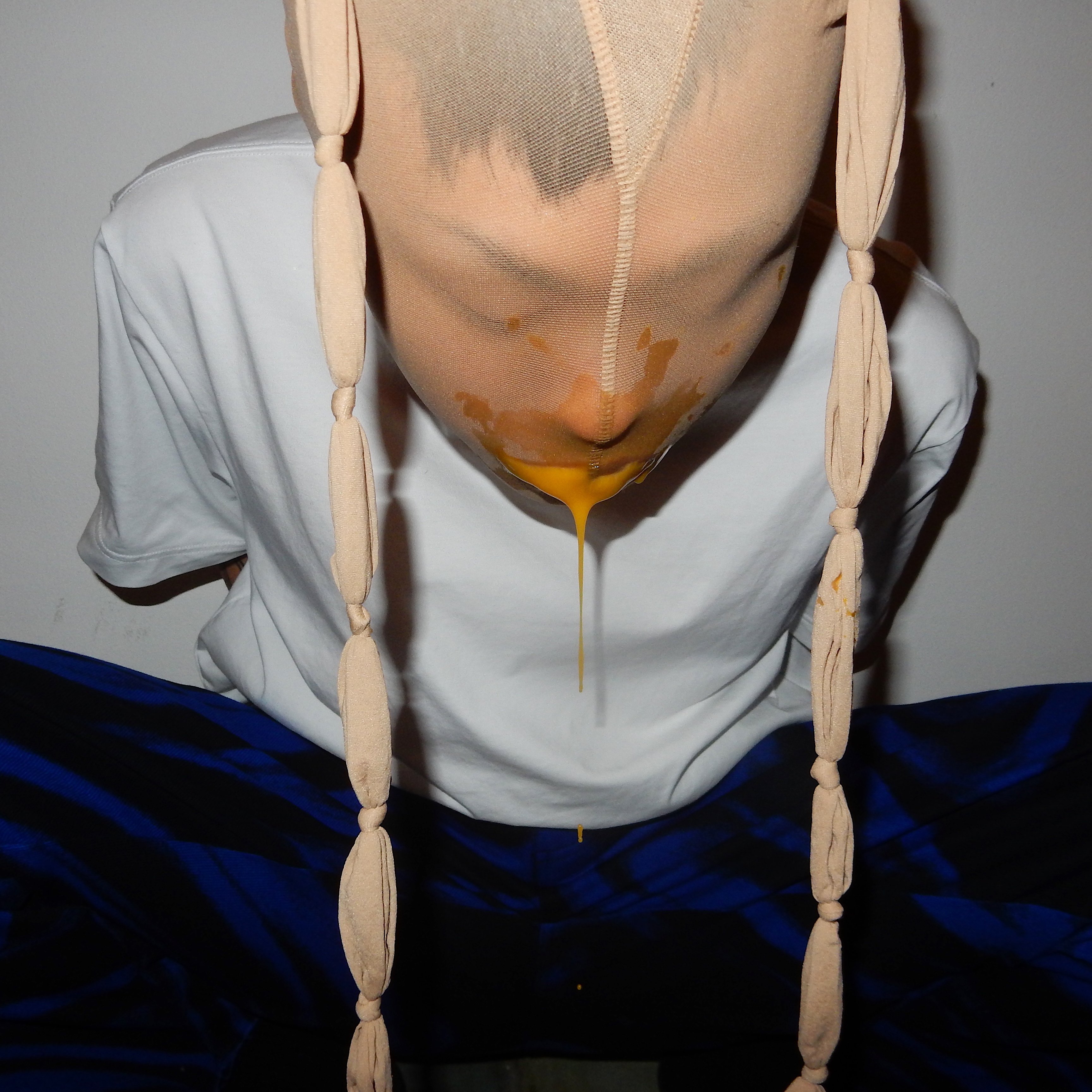 Person vomiting an orange liquid, with flesh-colored tights on the head, from Funkenstein