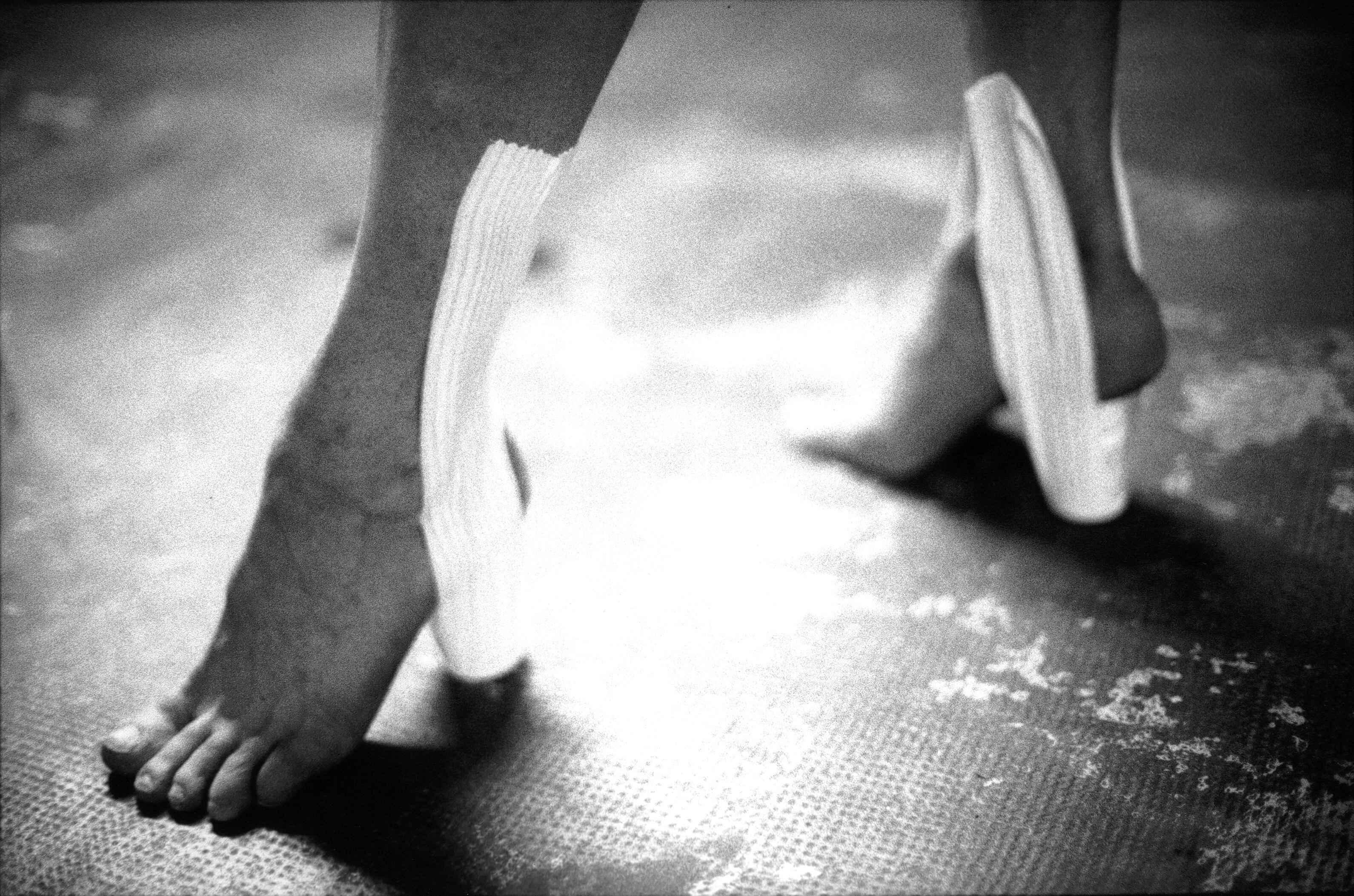 Close-up of bare feet wearing heels made from medical straps, extract from Good Boy