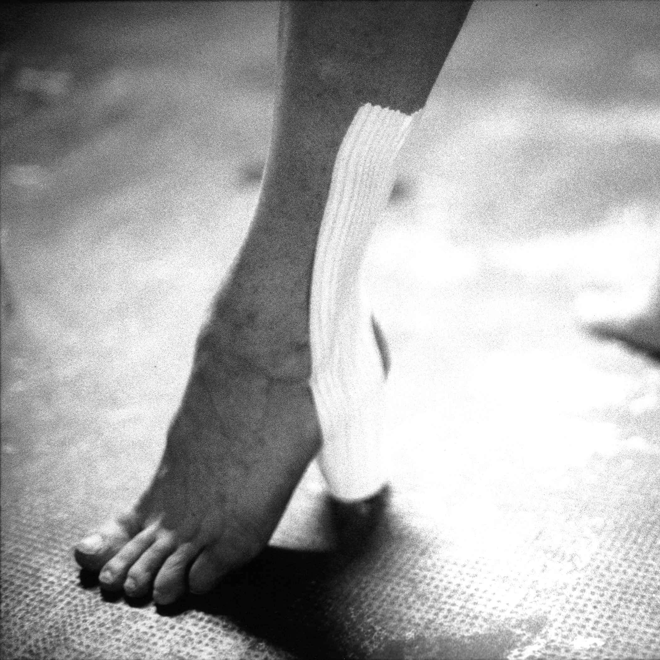 Close-up of bare feet wearing heels made from medical straps, extract from Good Boy