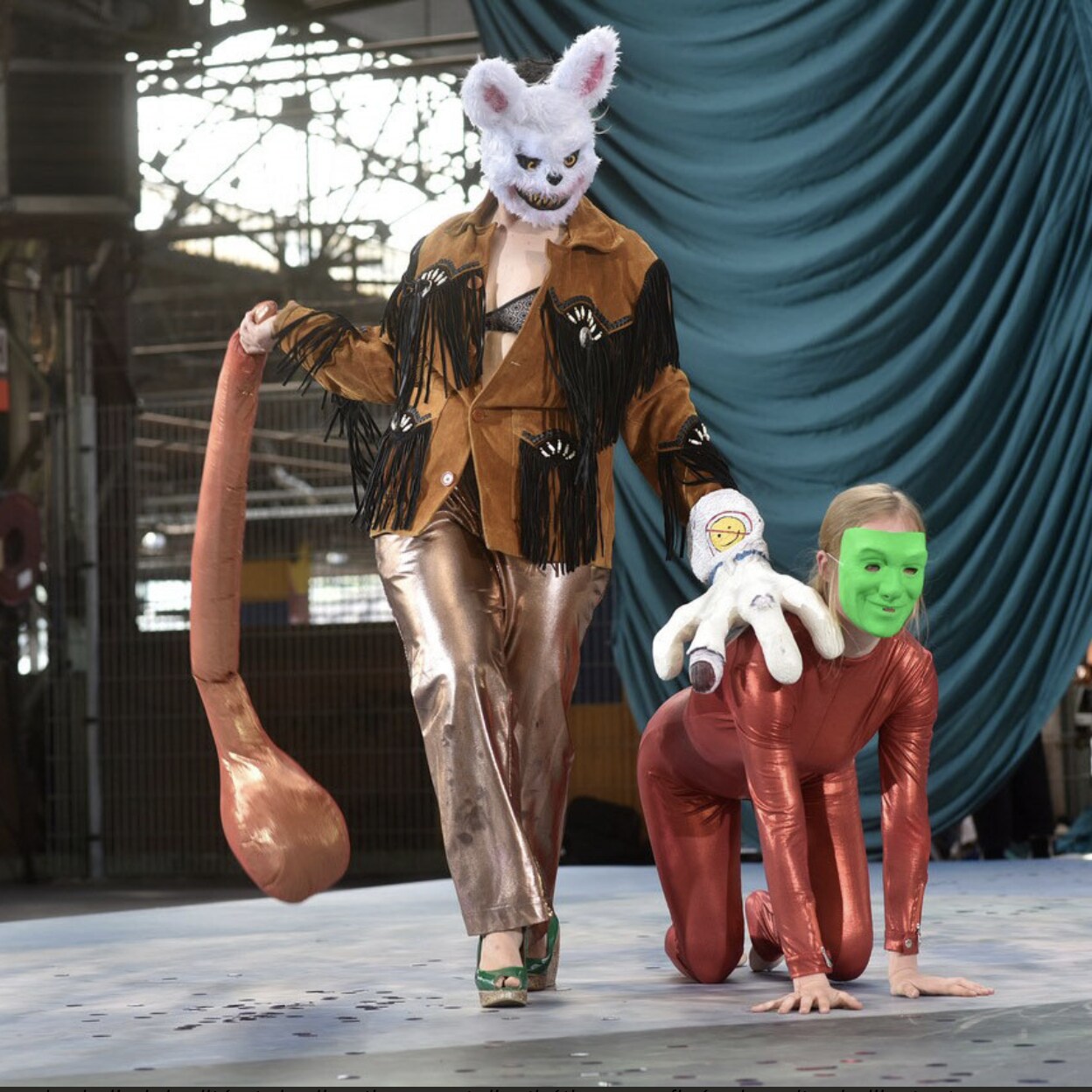 Two masked people on stage, one standing and one on all fours, from Midi Minuit Fantastico