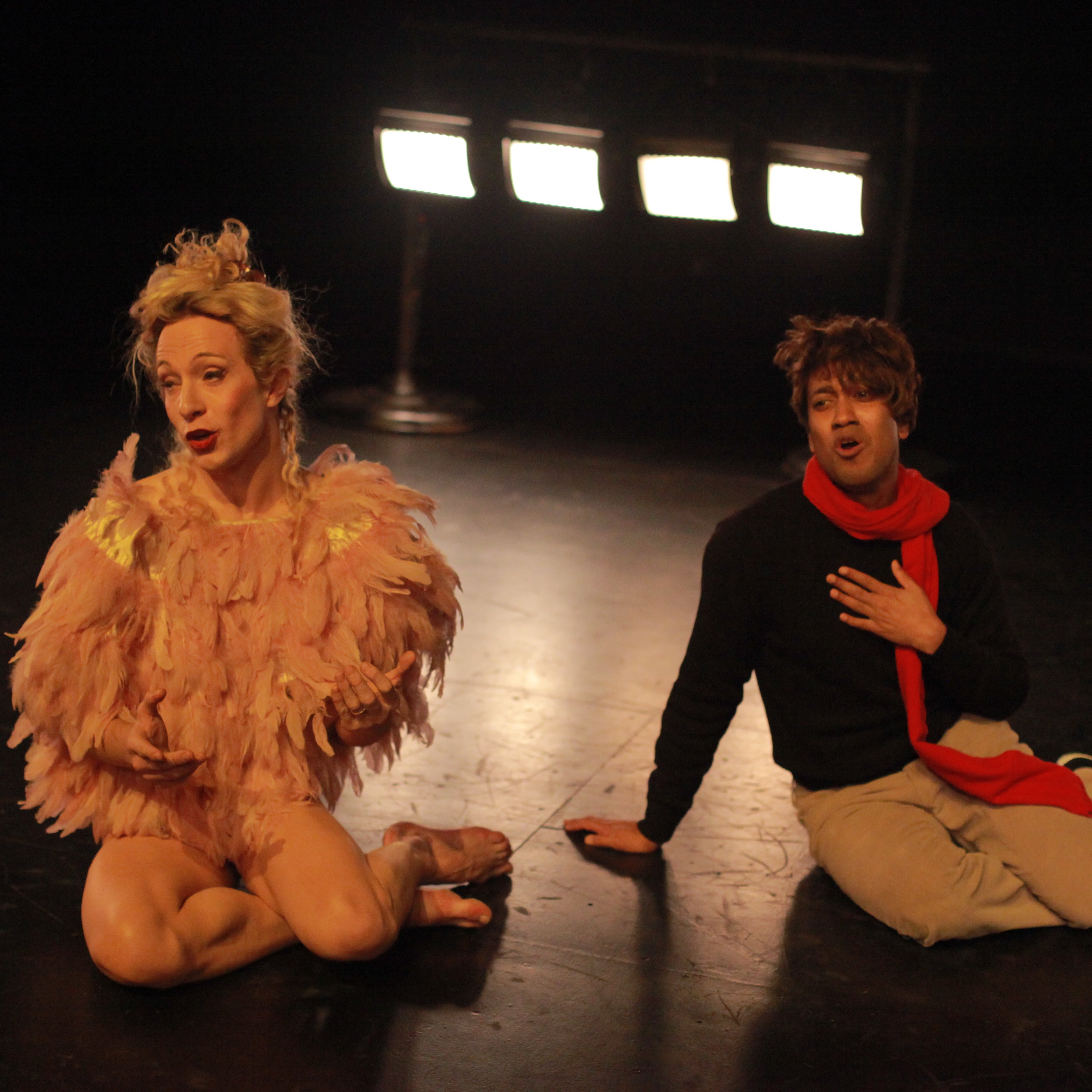 Two dancers sitting on the floor, mouths agape